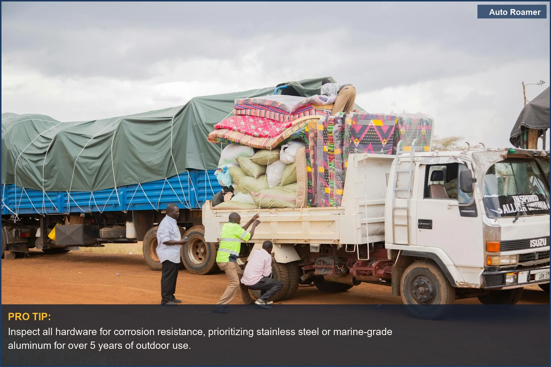 Loading camping gear onto a truck with a canopy in a rural setting under cloudy skies.