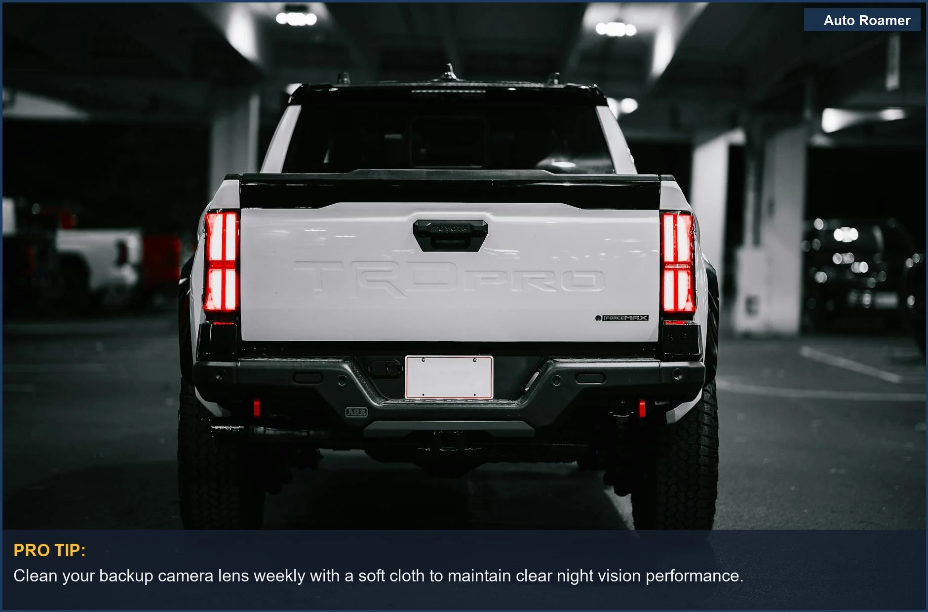 Vista trasera de una camioneta blanca en un garaje de estacionamiento por la noche, destacando las luces traseras y la visibilidad de la cámara.