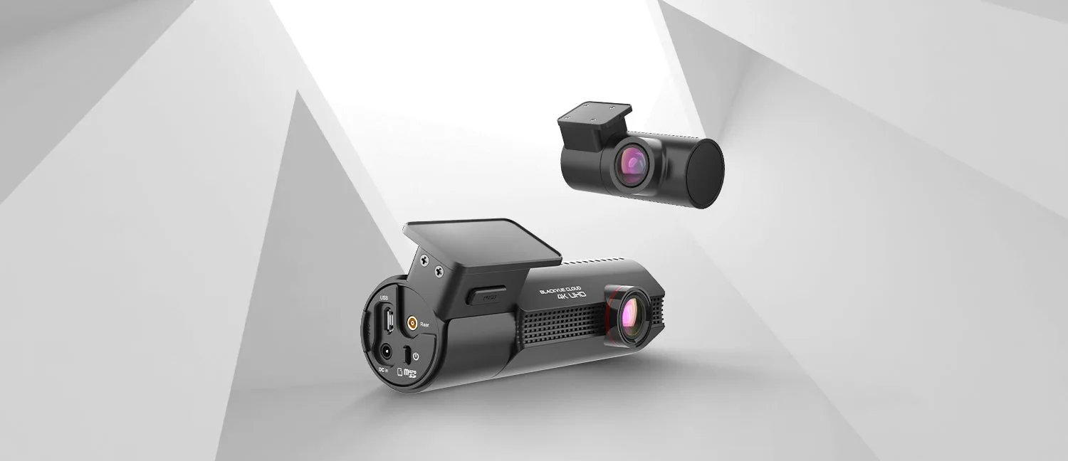 BlackVue dash cam shown as a black cylindrical front unit with a red-ringed lens alongside a smaller rear camera on a light studio background, the BlackVue hardware in a BlackVue versus Thinkware comparison