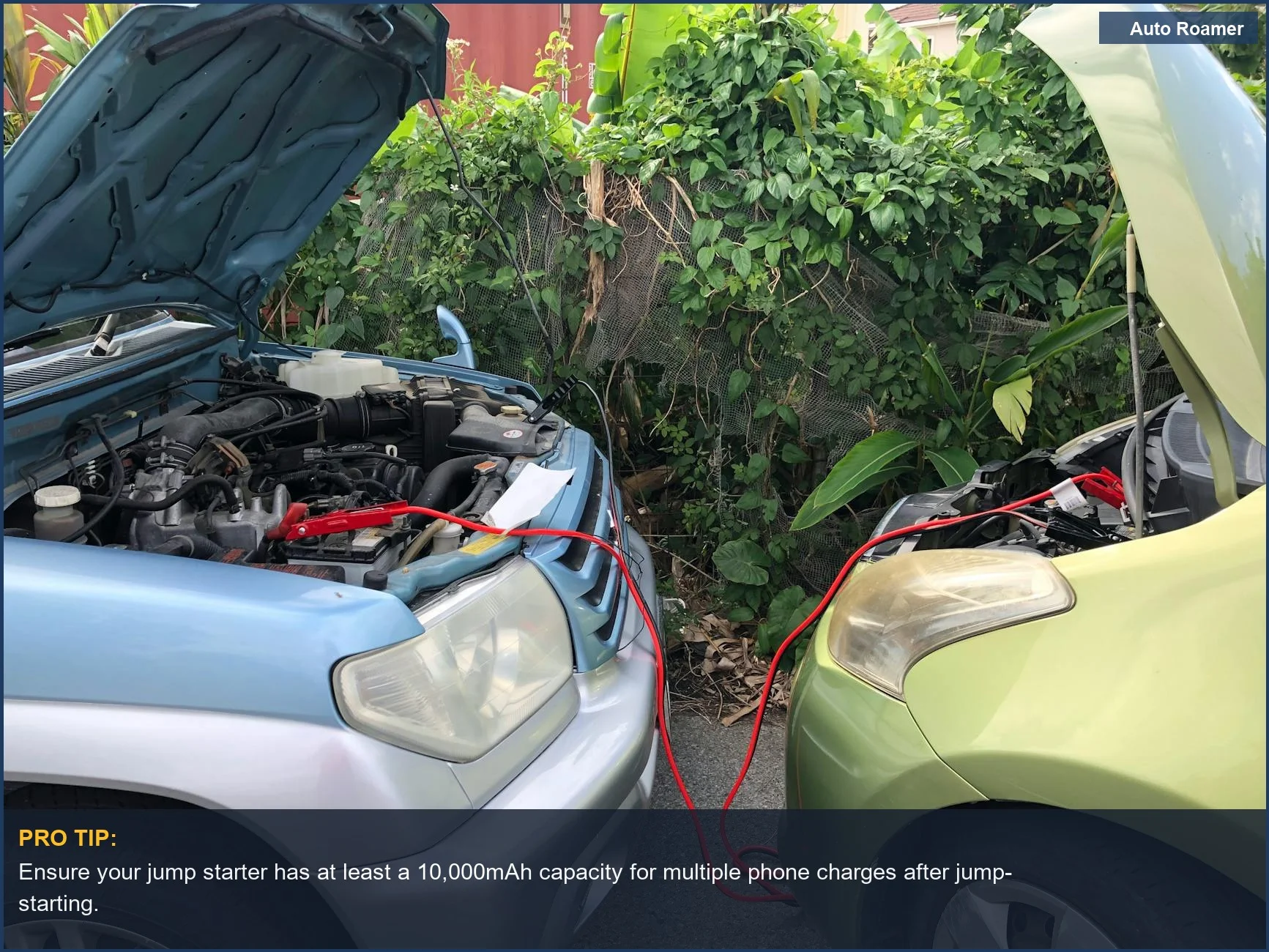 Two cars connected with jumper cables in a parking lot, demonstrating a jump starter power bank's primary function.