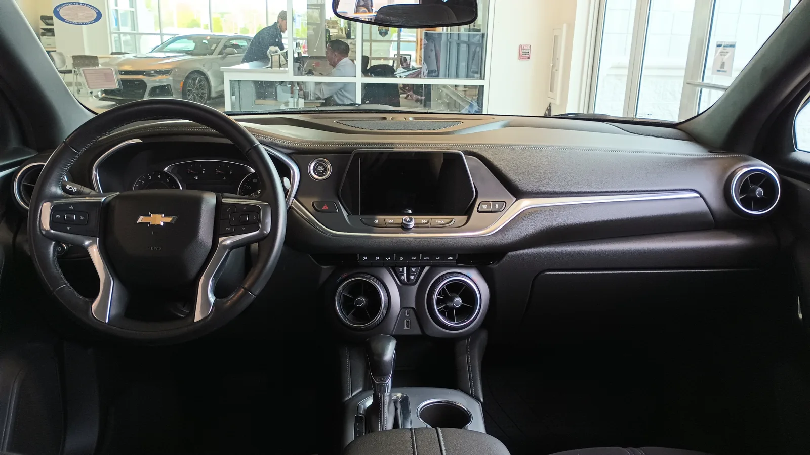 Interior of a Chevrolet Blazer showing the black dashboard, steering wheel with Chevrolet badge, center touchscreen and round vents, relevant to sleeping inside the cabin