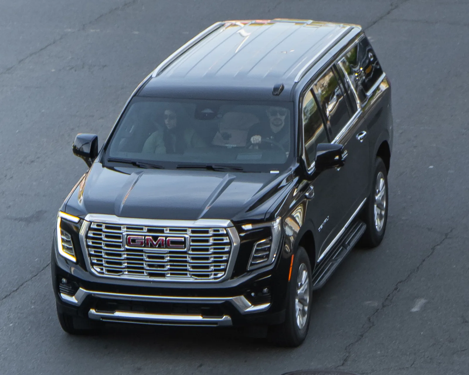Black current-generation GMC Yukon Denali full-size SUV on pavement seen from a high front three-quarter angle, the large SUV used for car camping