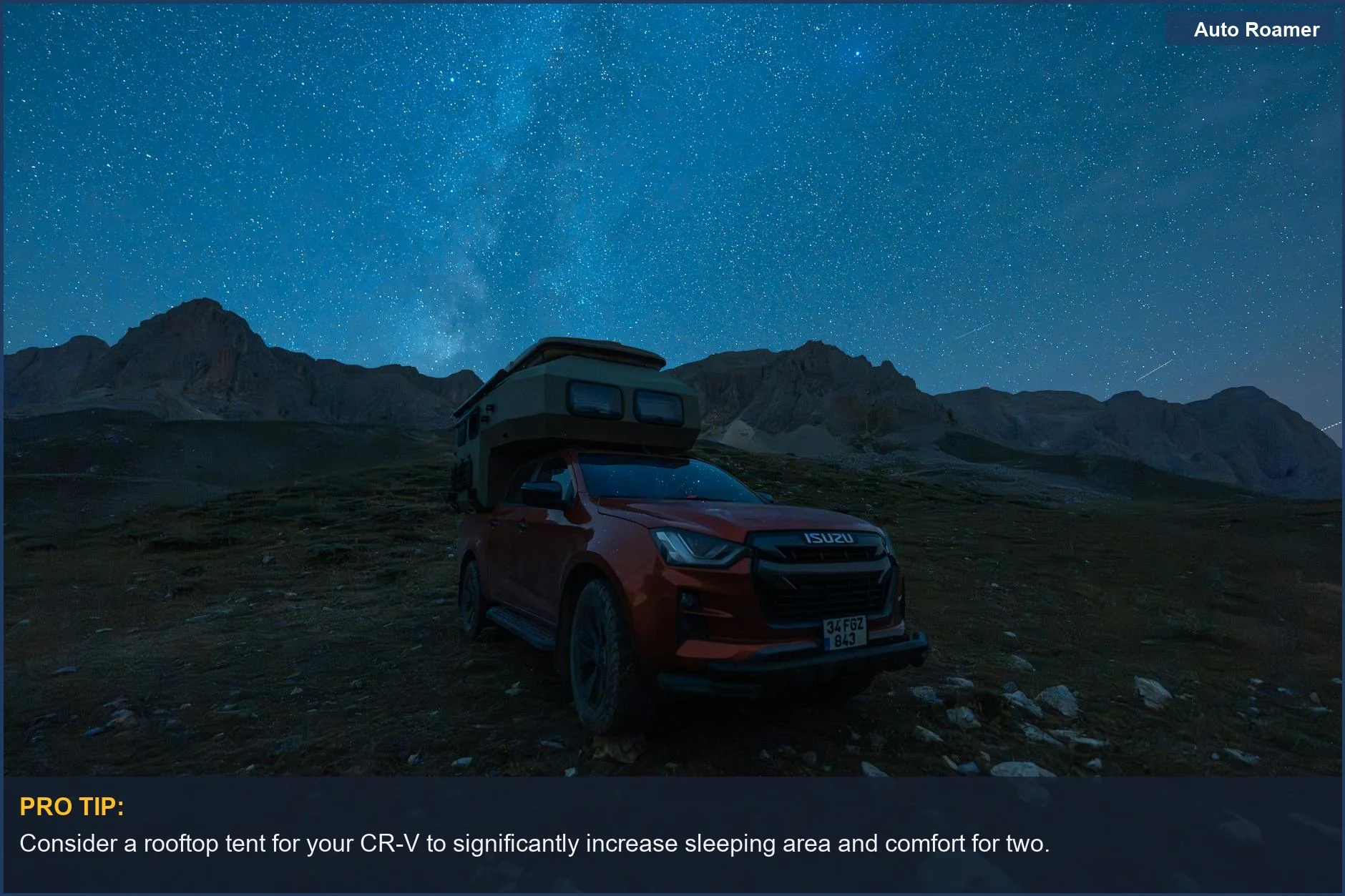 Red Honda CR-V with rooftop tent under a mountain starry night sky.