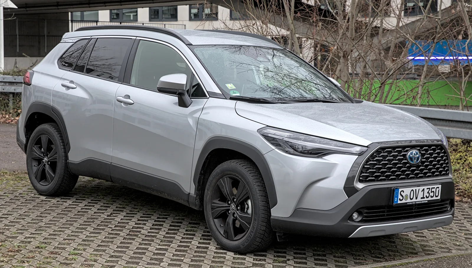 A silver Toyota Corolla Cross Hybrid parked on pavers, the compact this guide compares for sleeping