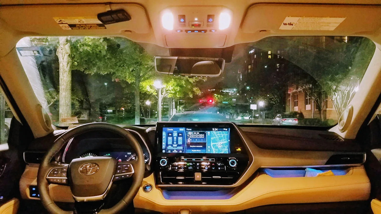 The lit dashboard and screen inside a Toyota Highlander at night, the cabin you sleep in