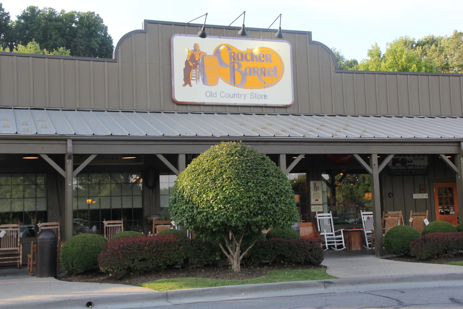 The storefront and rocking-chair porch of a Cracker Barrel Old Country Store, where people sleep in a car overnight