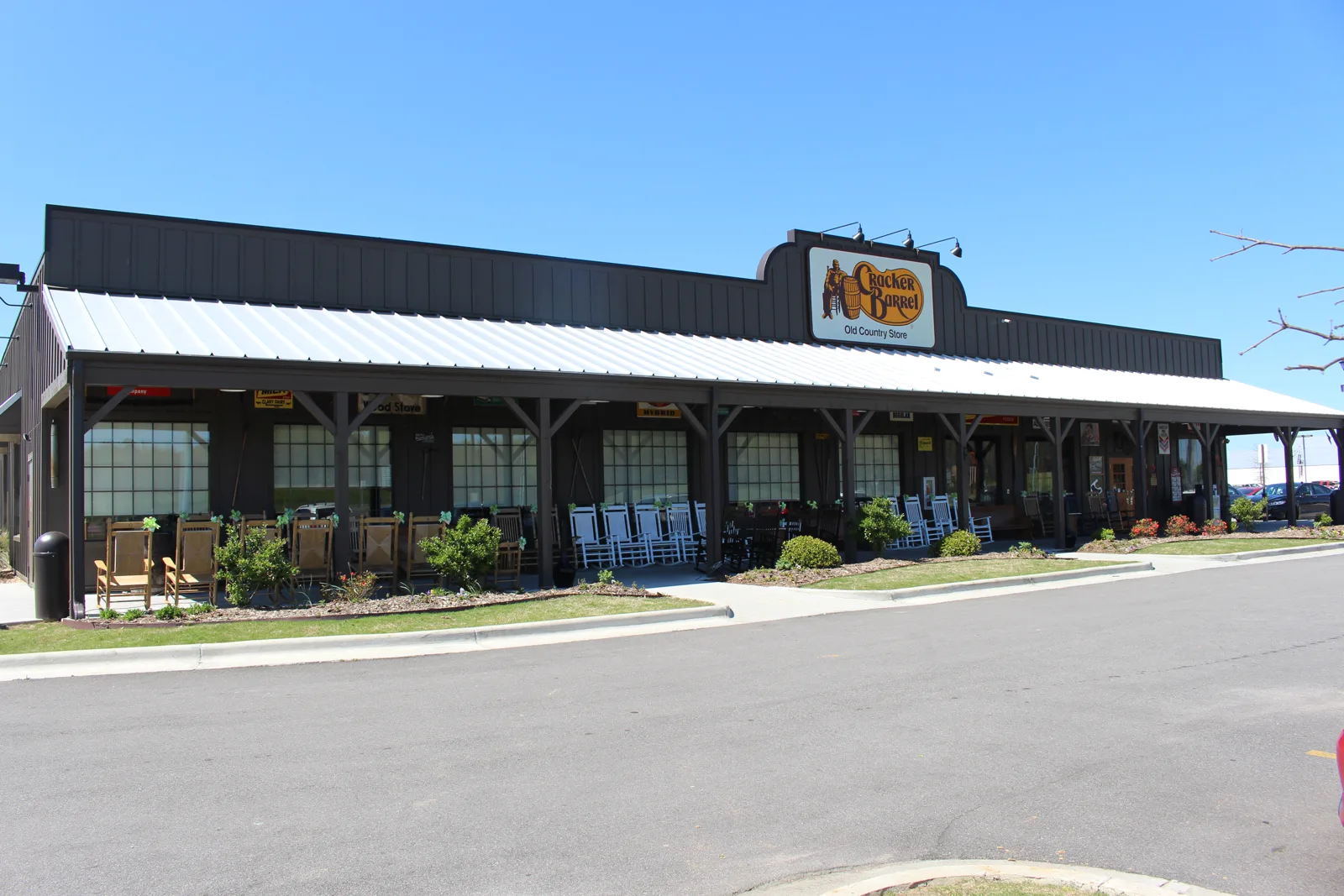 A Cracker Barrel restaurant and its parking lot under blue sky, a spot people sleep in a car overnight