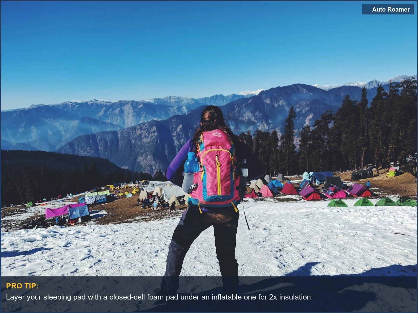 A woman enjoys a scenic winter car camping trip, surrounded by colorful tents and vast snowy mountain vistas.