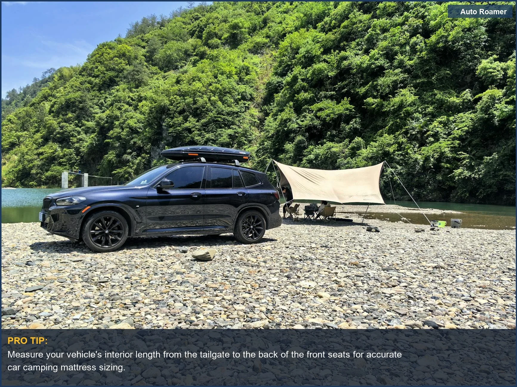 A black SUV set up for car camping beside a river, showcasing a comfortable sleeping space.