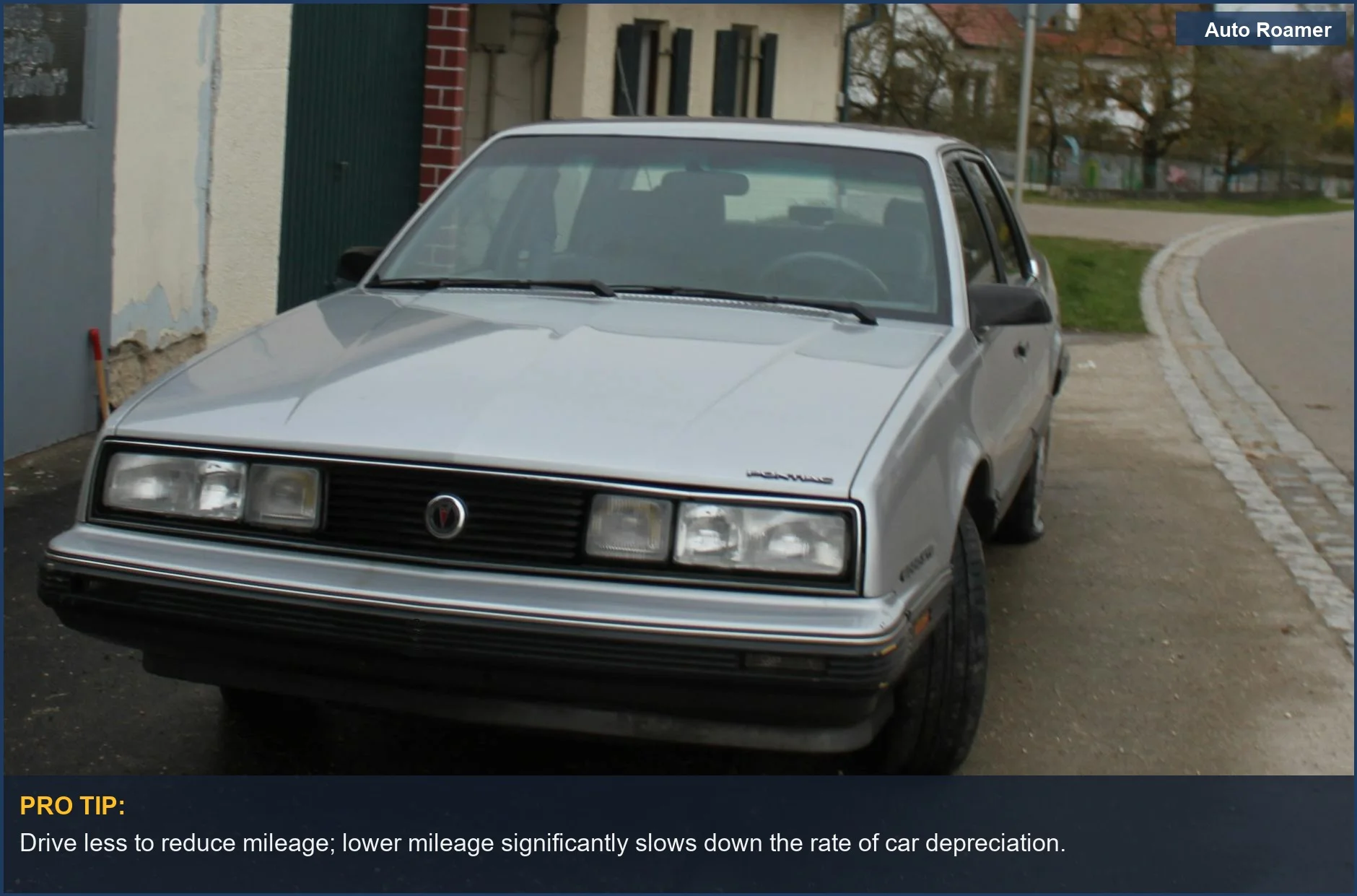 Silver sedan parked on an urban street near buildings, illustrating car depreciation per month.