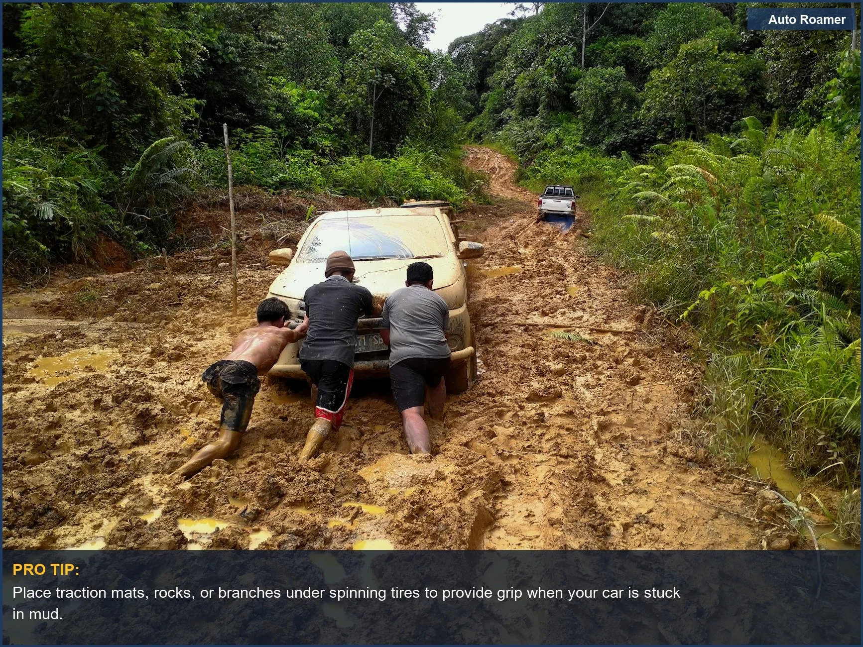 Three men pushing a car through a muddy forest road in Indonesia, illustrating getting a car out of mud.