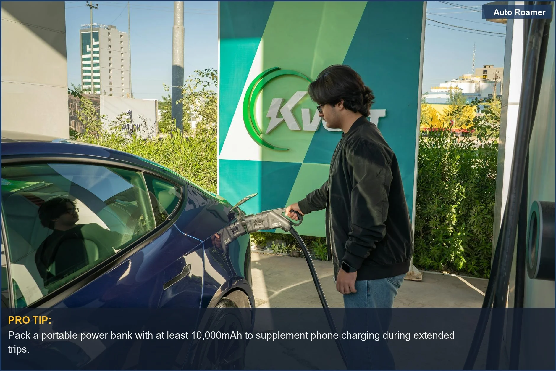 Hombre joven cargando un Tesla Model 3 en una estación de carga para vehículos eléctricos al aire libre, destacando la conveniencia de cargar dispositivos.