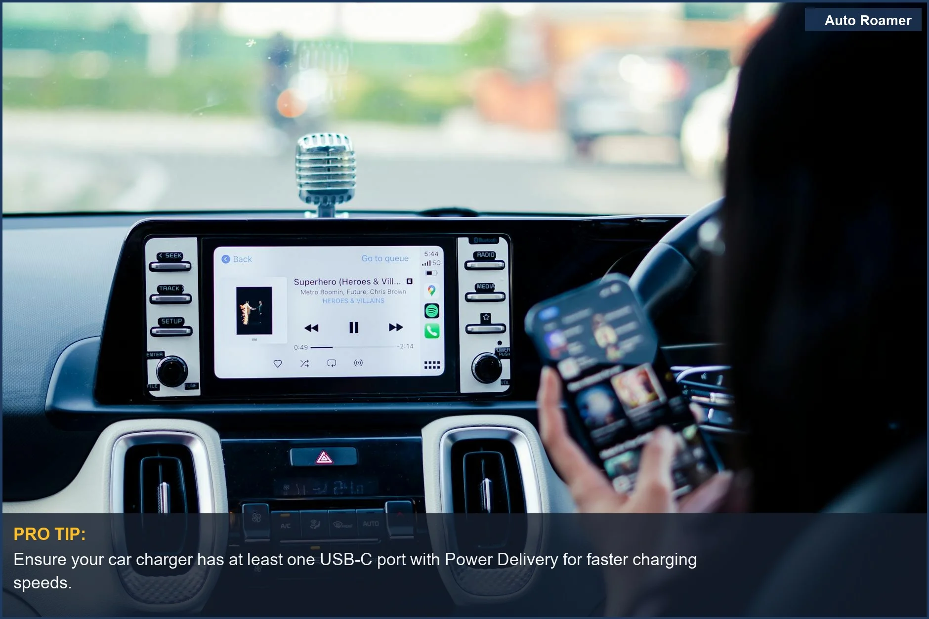 Modern car dashboard with touchscreen, person charging a smartphone with a car USB charger for multiple devices.