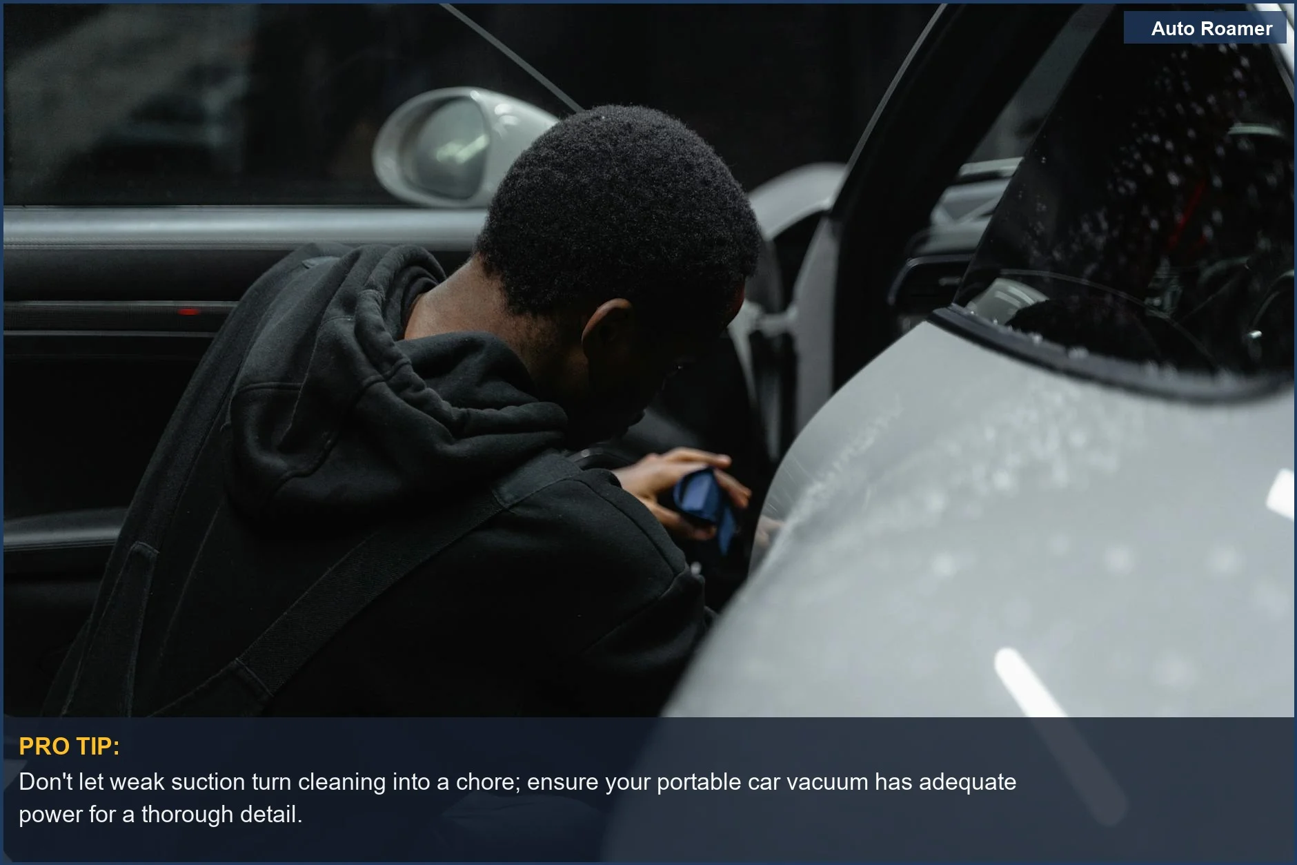 Persona detallando meticulosamente el interior de un coche de lujo con una aspiradora portátil, destacando la precisión y el cuidado de las características del aspirador de coche.