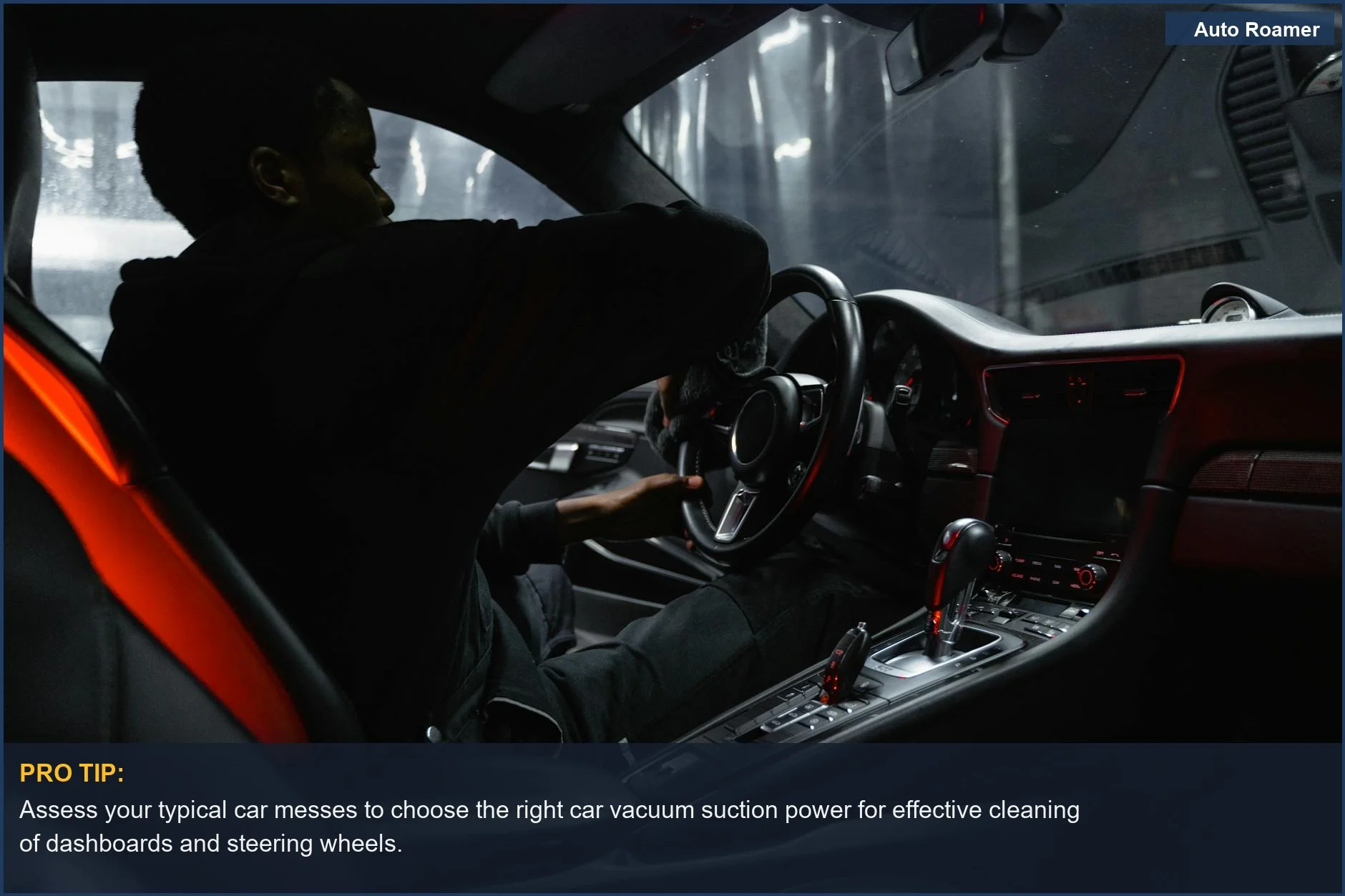 Hombre afroamericano limpiando el salpicadero y el volante del coche con una aspiradora portátil, centrándose en elegir el aspirador de coche adecuado.