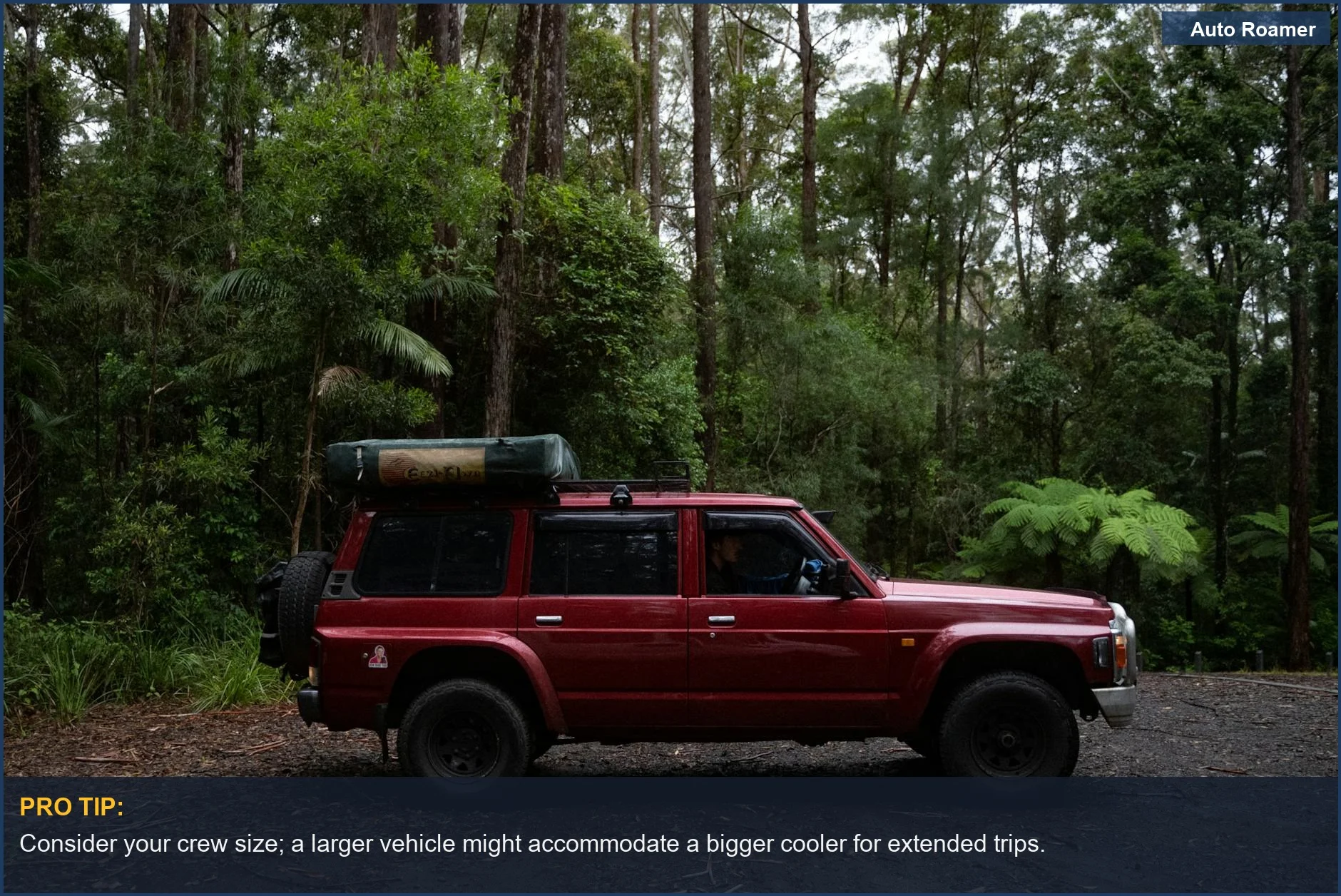 SUV rojo aparcado en un camino forestal, mostrando la preparación del vehículo para el camping en coche con un portaequipajes en el techo.