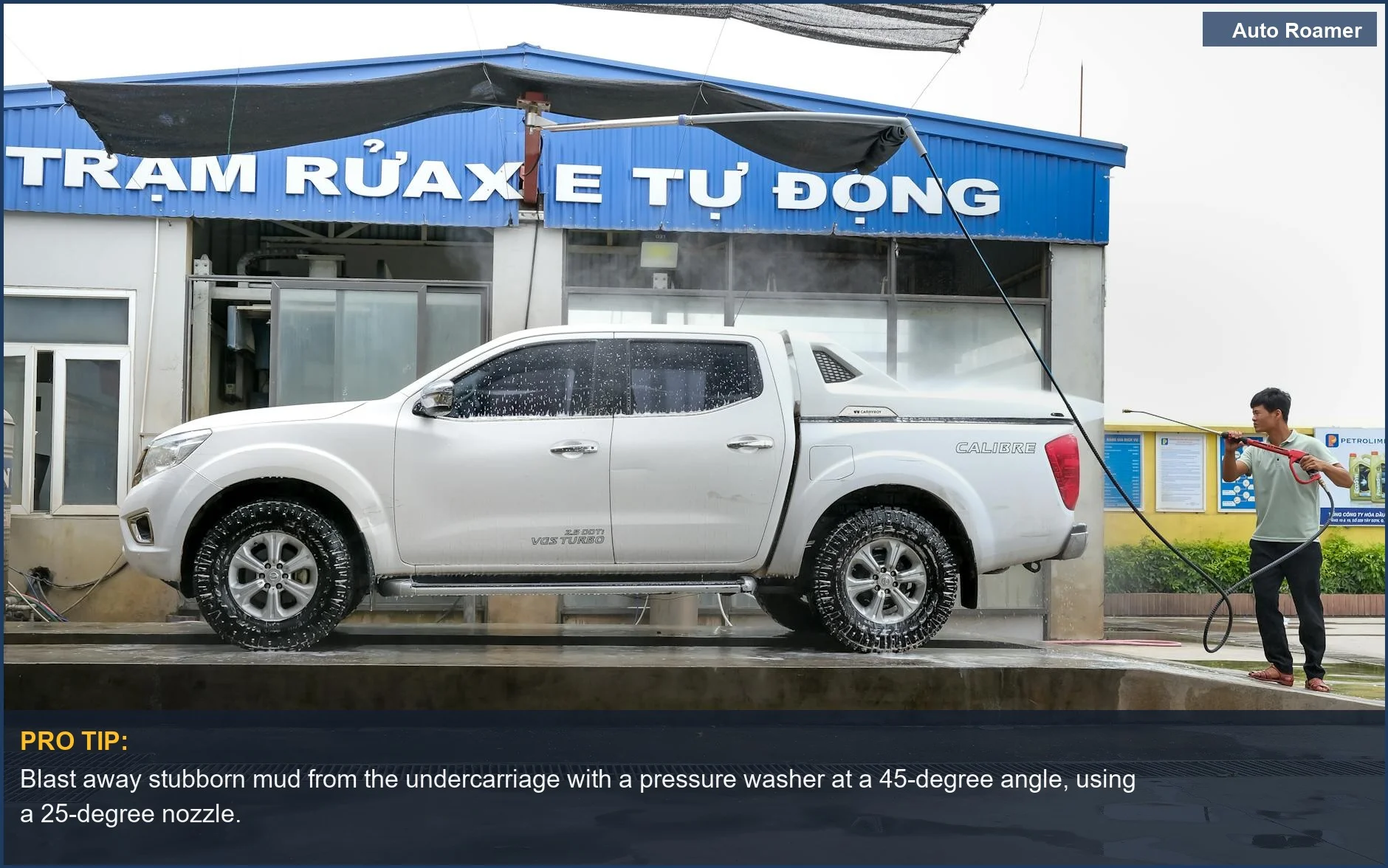 Adult pressure washing a muddy white pickup truck exterior to clean car camping mess.