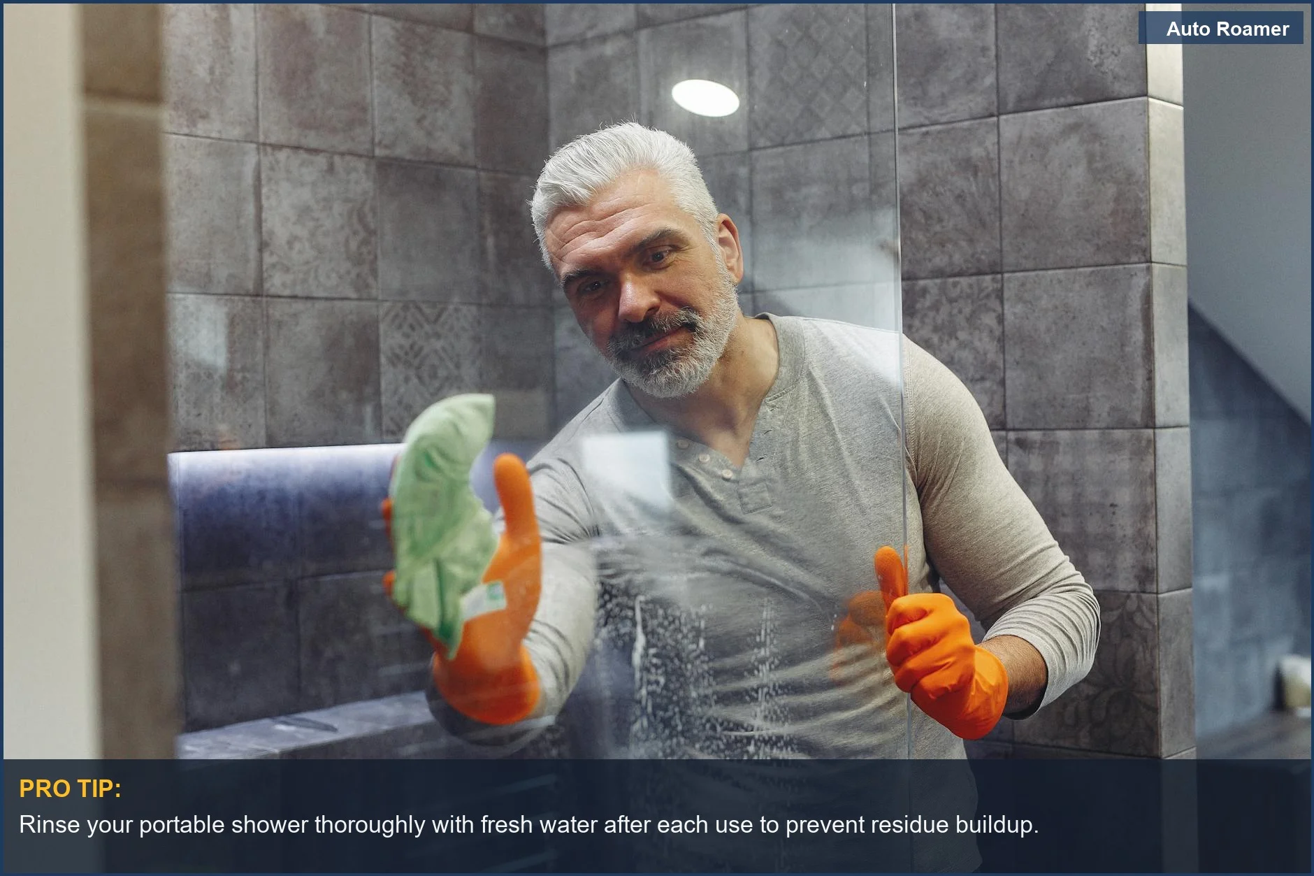 Hombre con barba y guantes limpiando meticulosamente el cristal de una ducha portátil para un mantenimiento óptimo de la ducha de camping.