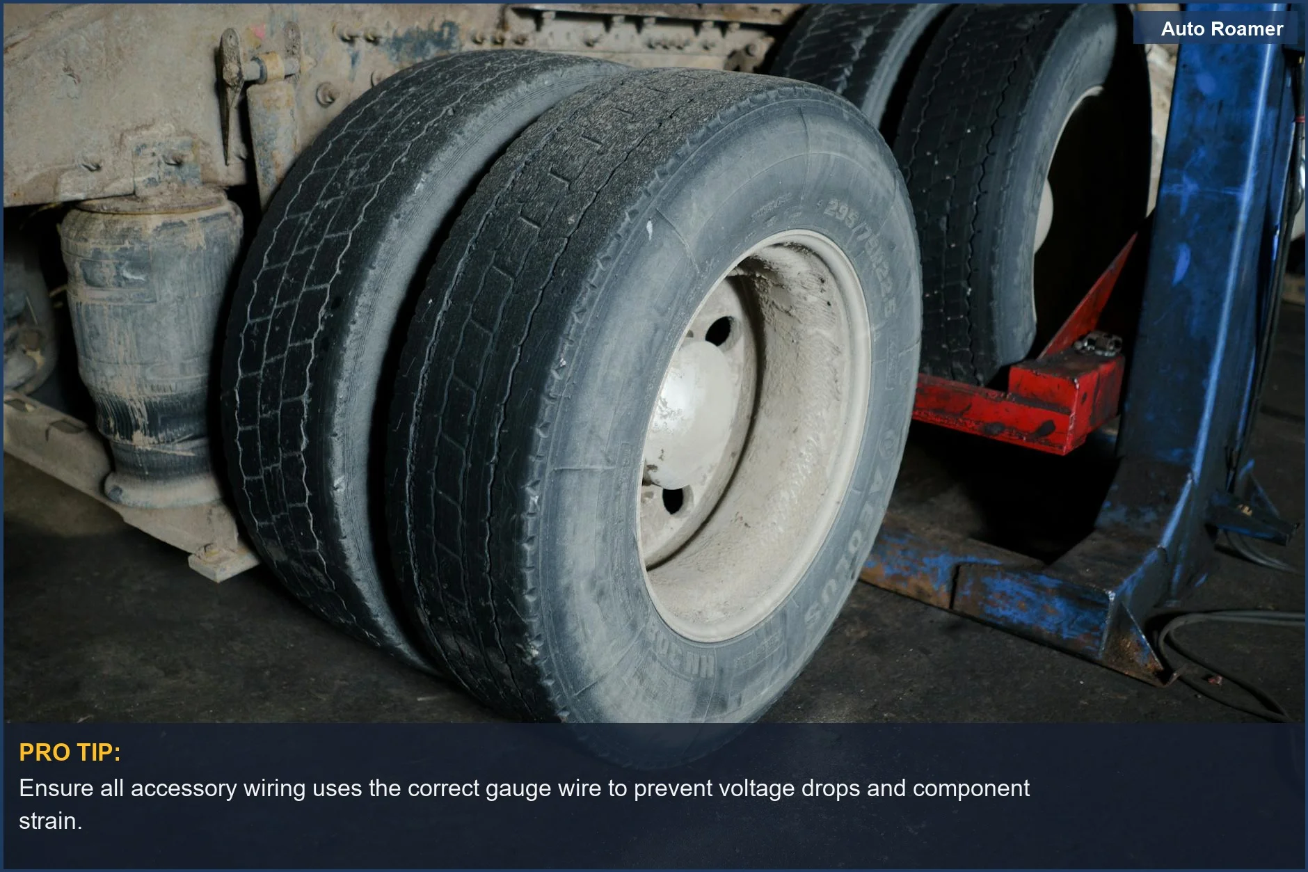 Close-up of truck tires in a garage awaiting maintenance, illustrating electrical system strain from bad accessory installs.
