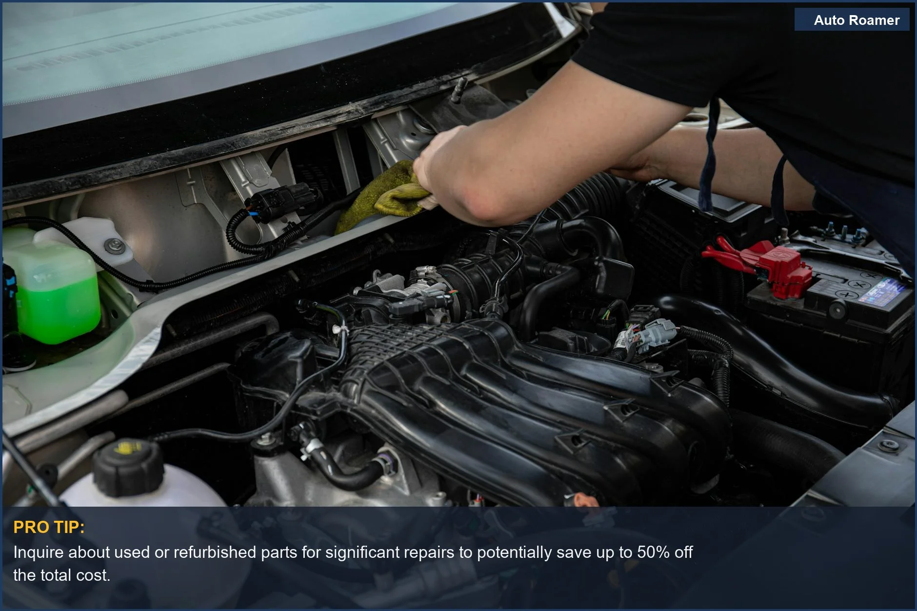 Close-up view of a mechanic's hands working on a complex car engine in a workshop.