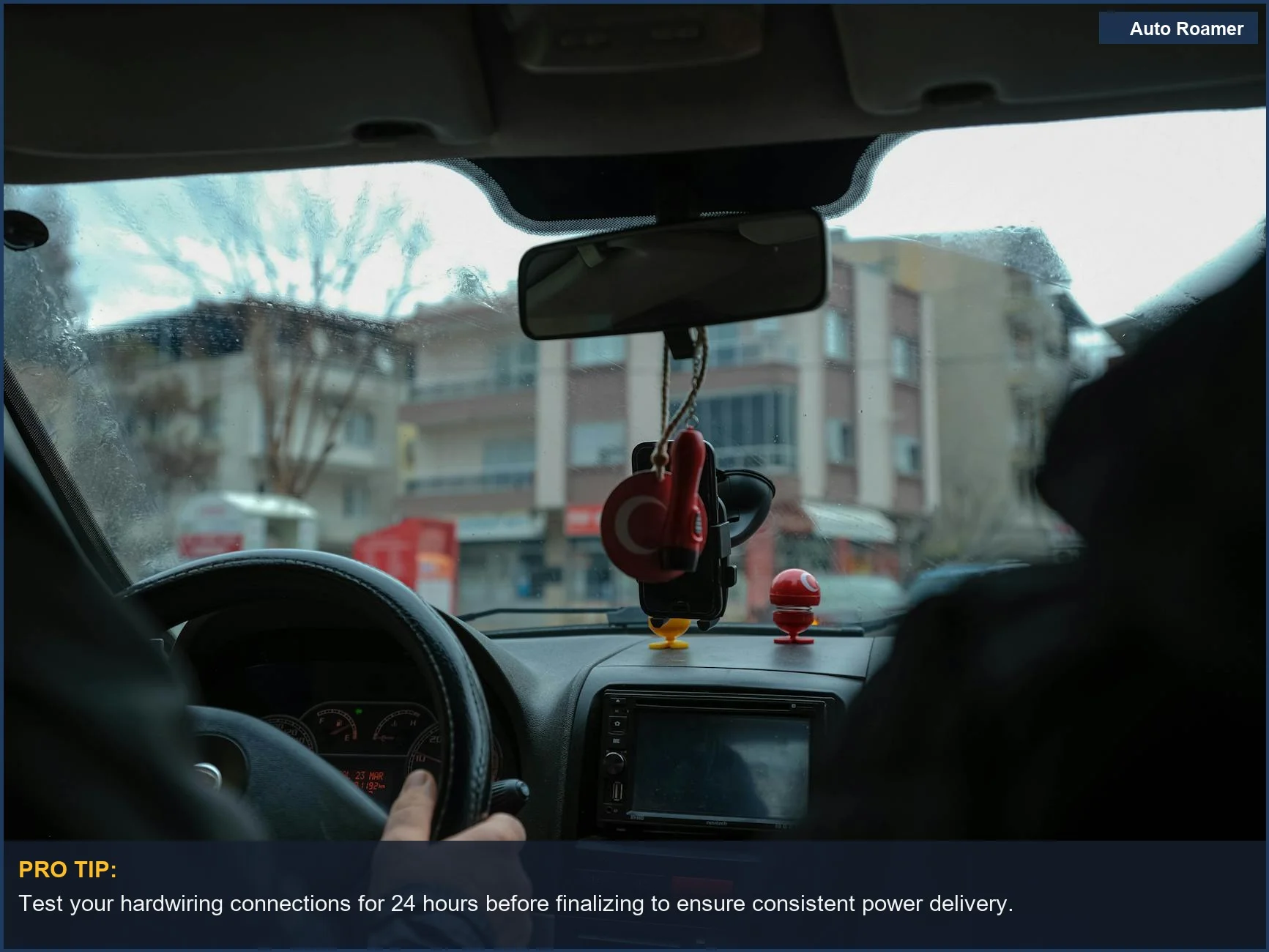 City street driving perspective from car interior, focusing on dashboard and rearview mirror for dash cam advice.