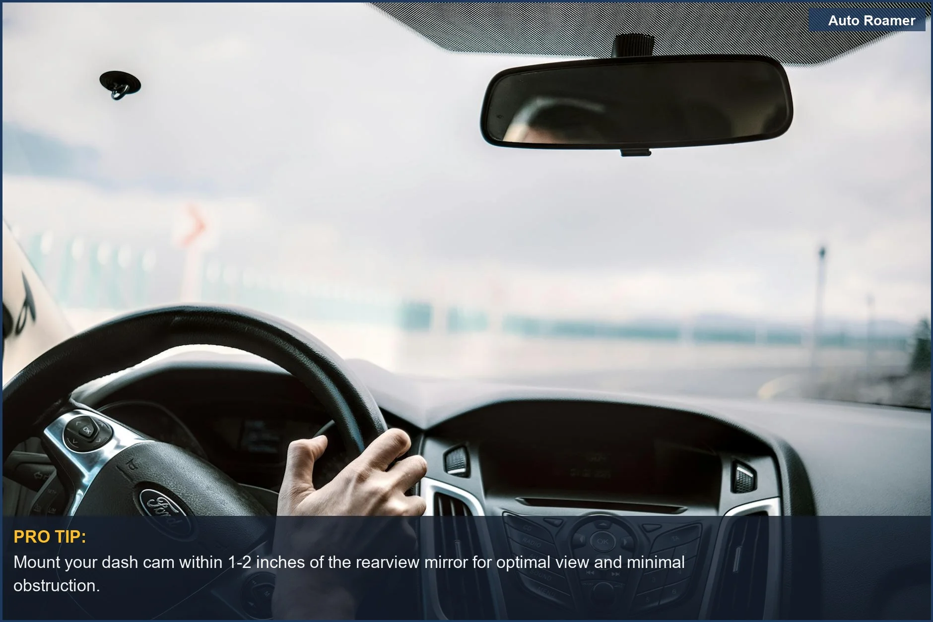 Driver's view inside car showing steering wheel, dash cam, and blurred road for easy dash cam mounting.