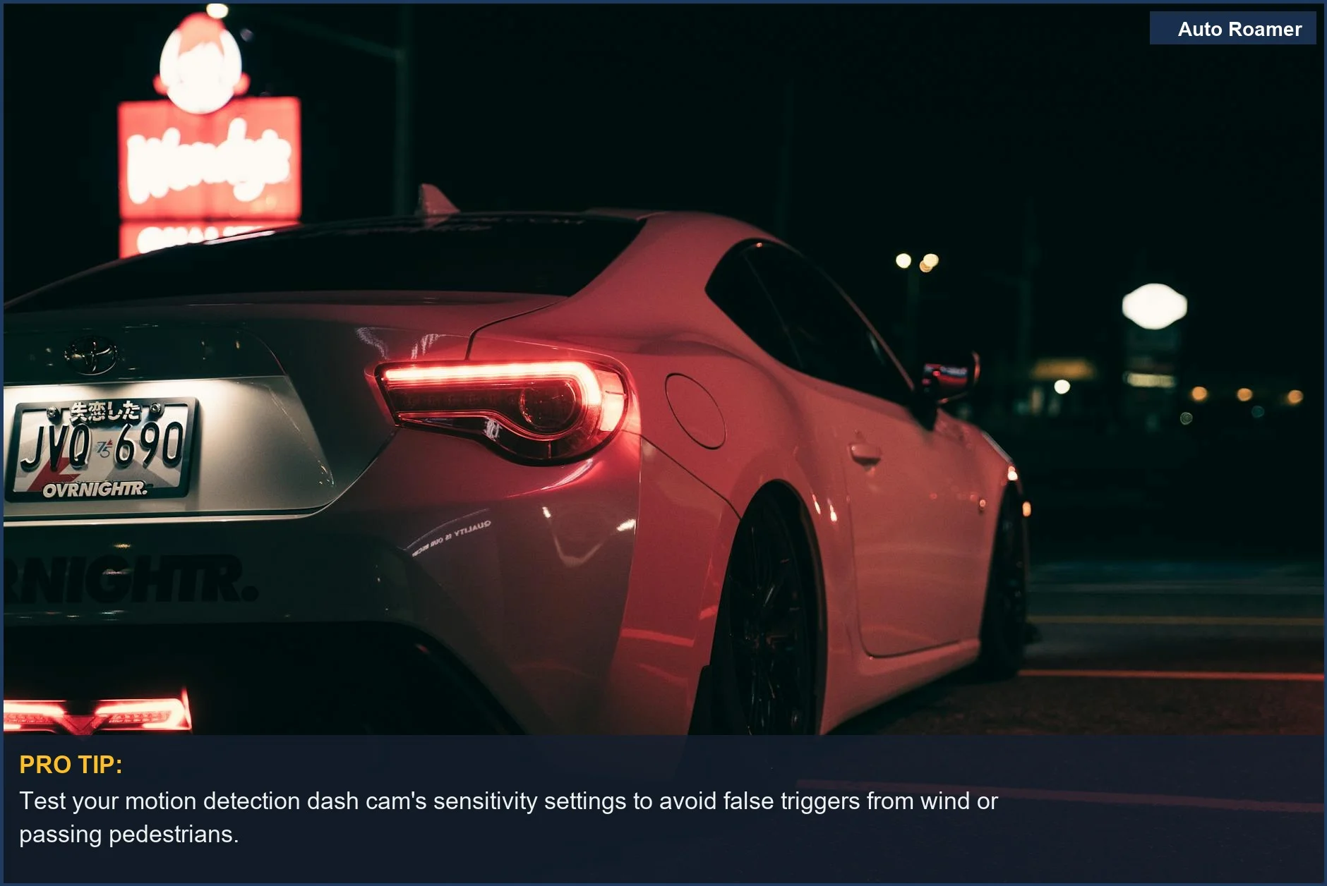 Sleek white sports car parked near a neon fast food sign at night, illustrating motion detection dash cam benefits.
