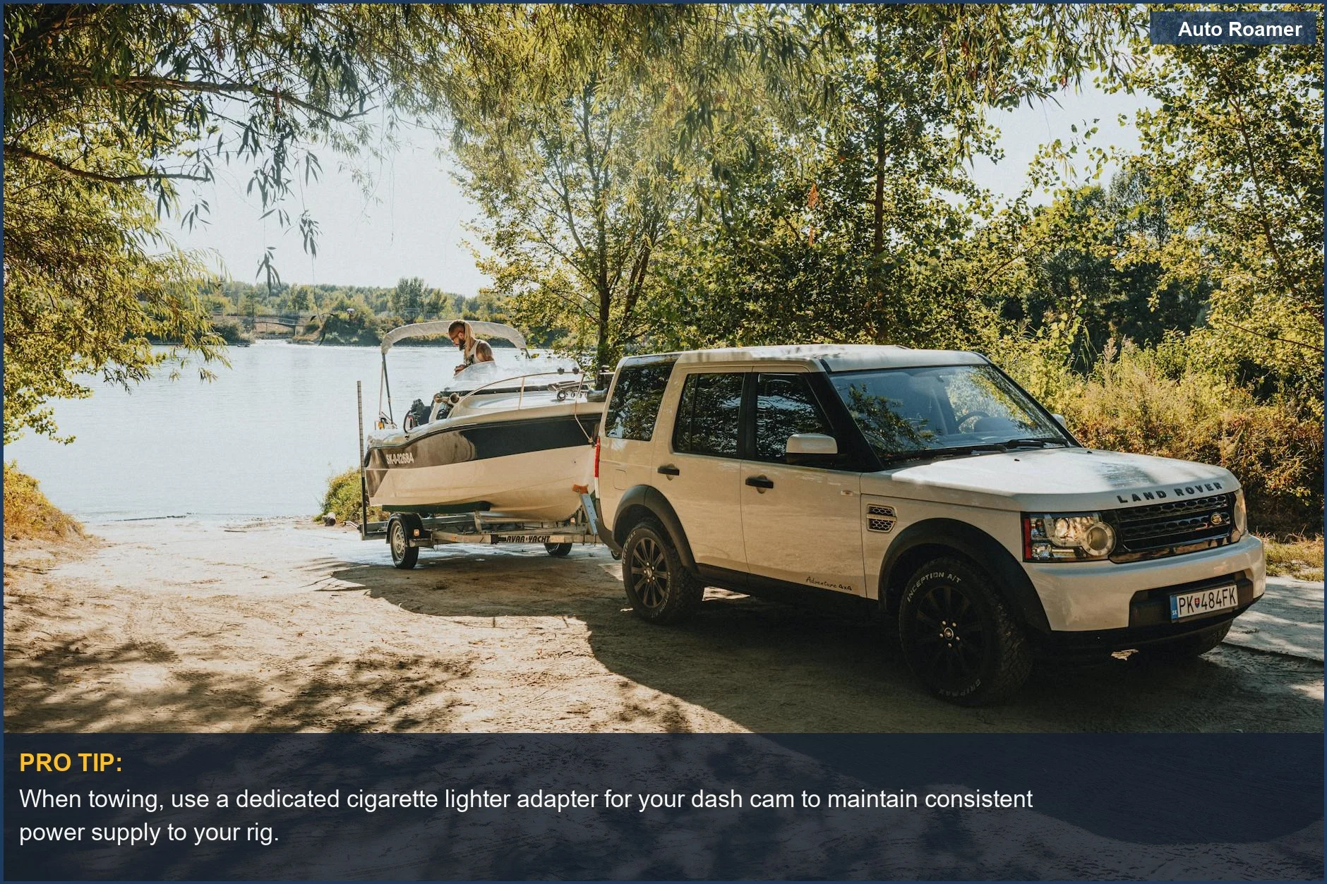 Land Rover towing a boat to a scenic lakeside on a sunny day, illustrating towing scenarios.