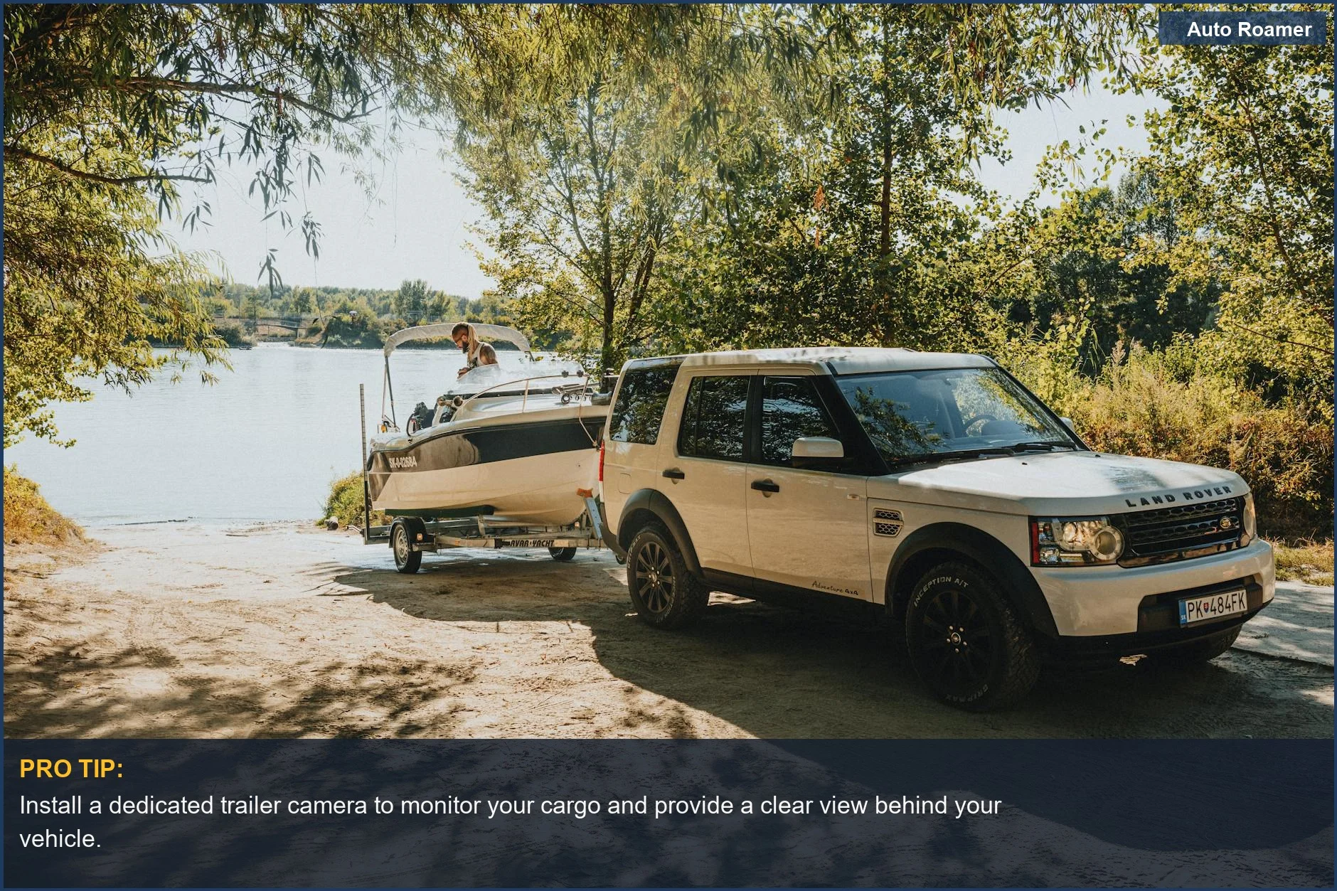Land Rover towing a boat to a lakeside, showing the advantage of a trailer camera for towing situations.
