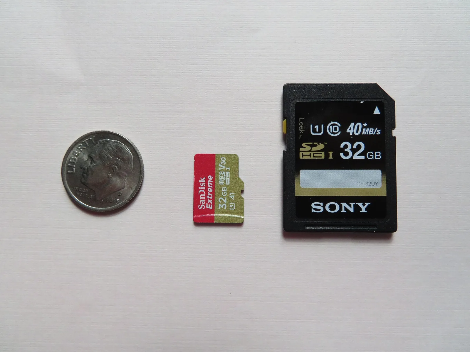 A microSD card and a full-size SD card next to a dime, the memory card you reformat or replace when a dash cam keeps restarting.