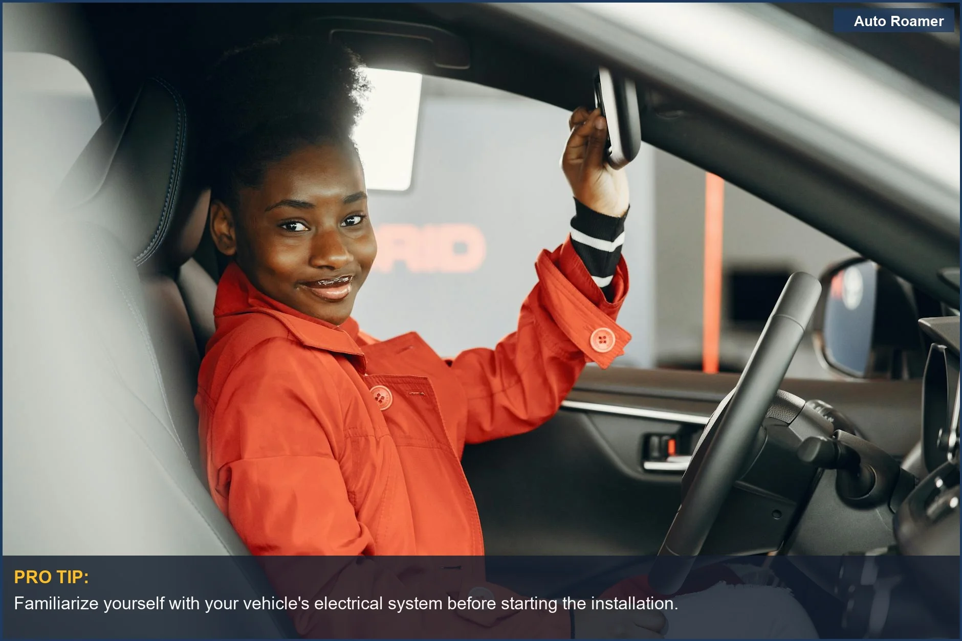Woman in a red jacket adjusting rearview mirror in a car.