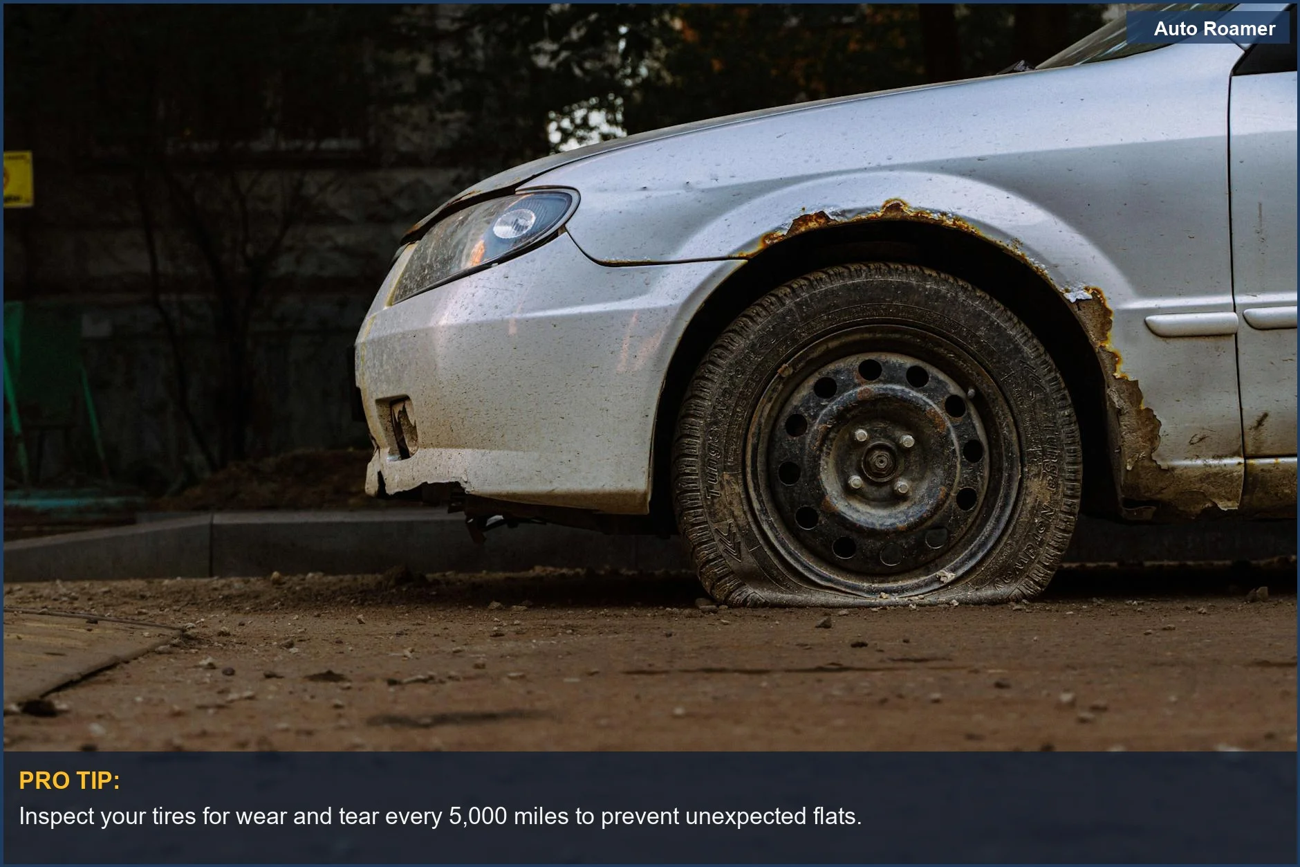 Close-up of a severely flat tire on a rusted car, illustrating the consequence of driving on a flat.