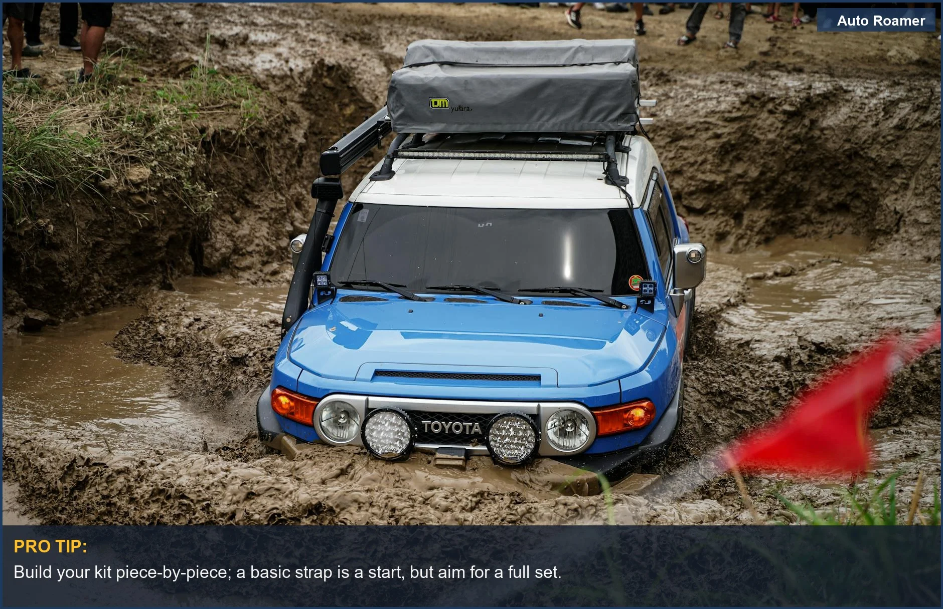 Blue SUV navigating muddy terrain, essential recovery kit components for off-road challenges.