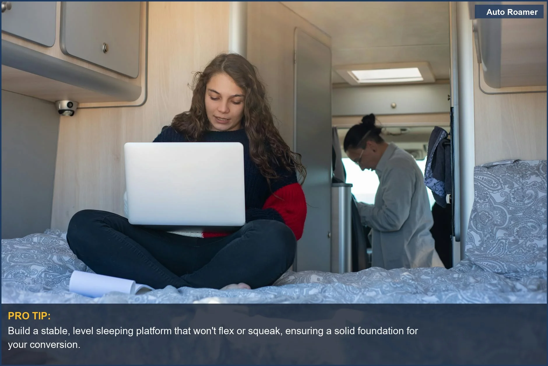 Young woman working on a laptop inside a converted camper van, highlighting mobile living.