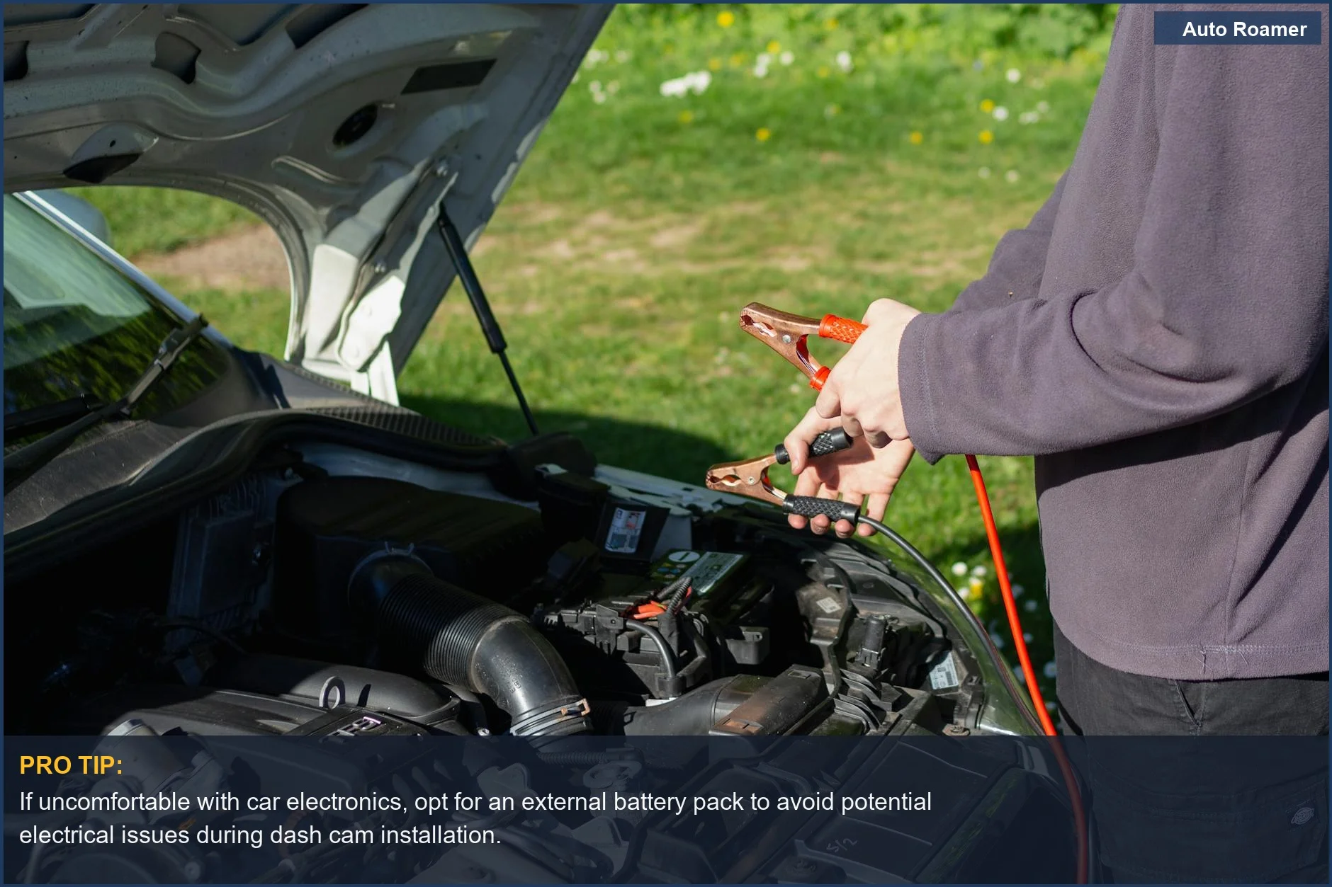 Man using jumper cables on a car engine, highlighting the importance of a healthy car battery for dash cam installation.