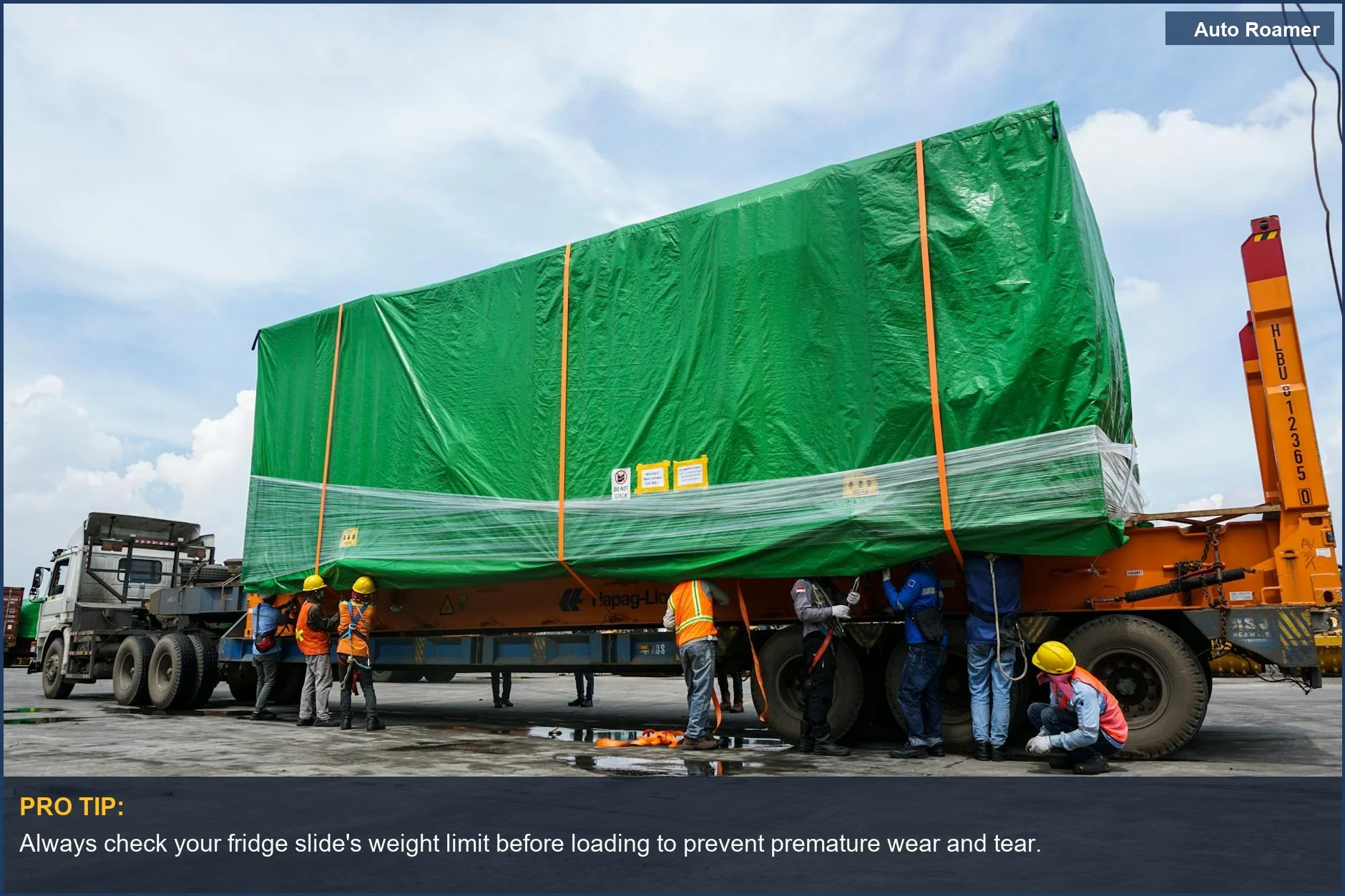 Industrial workers carefully load a heavy container onto a trailer, illustrating robust SUV cargo weight handling.