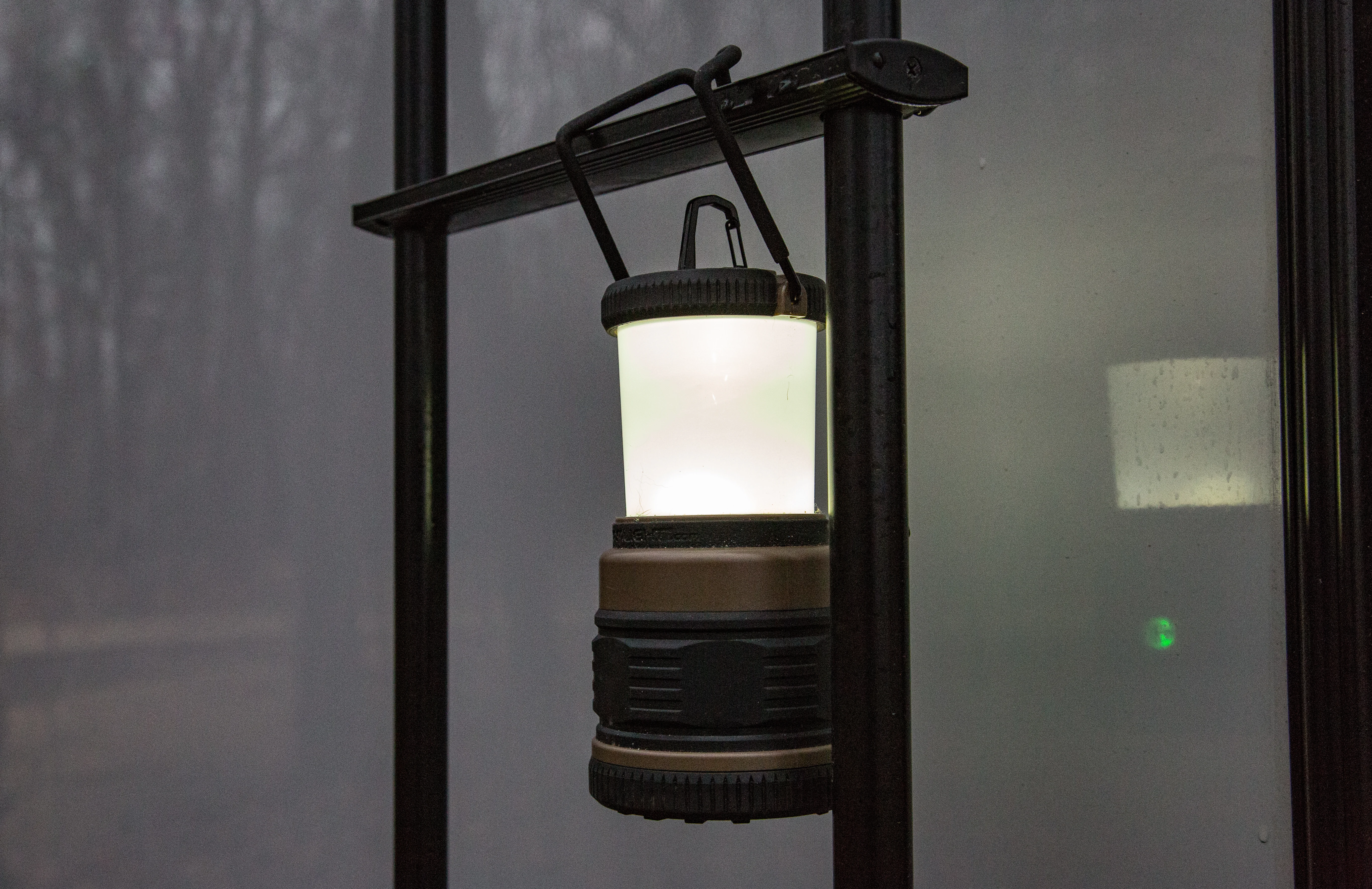 A Streamlight LED camping lantern lit at a campsite, an electric alternative to the propane and butane lanterns this guide compares.