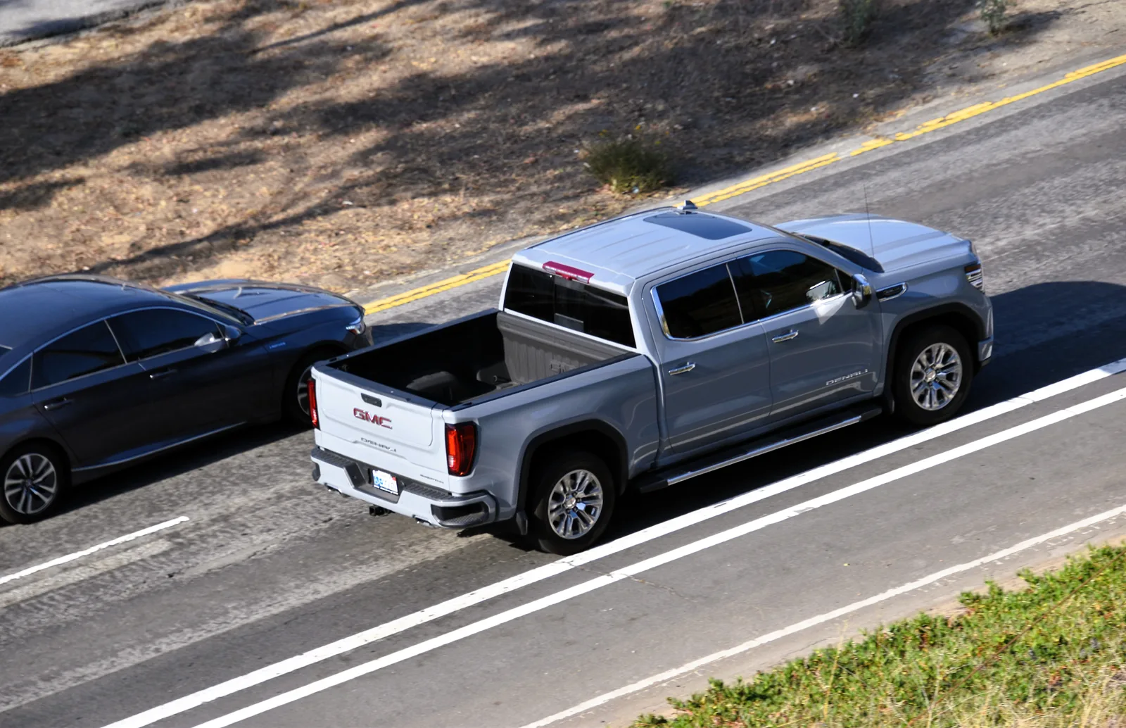 A silver GMC Sierra 1500 pickup seen from above showing its open truck bed, the camping bed this guide measures