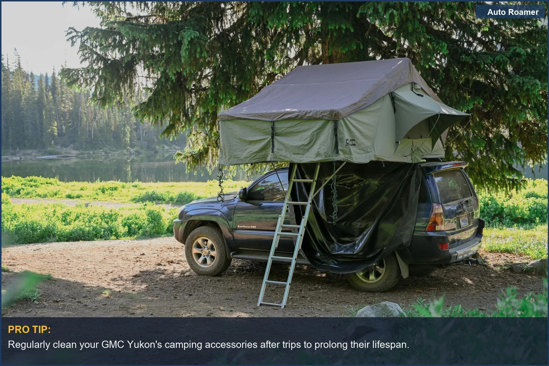GMC Yukon with rooftop tent parked at a peaceful campsite by a lake.