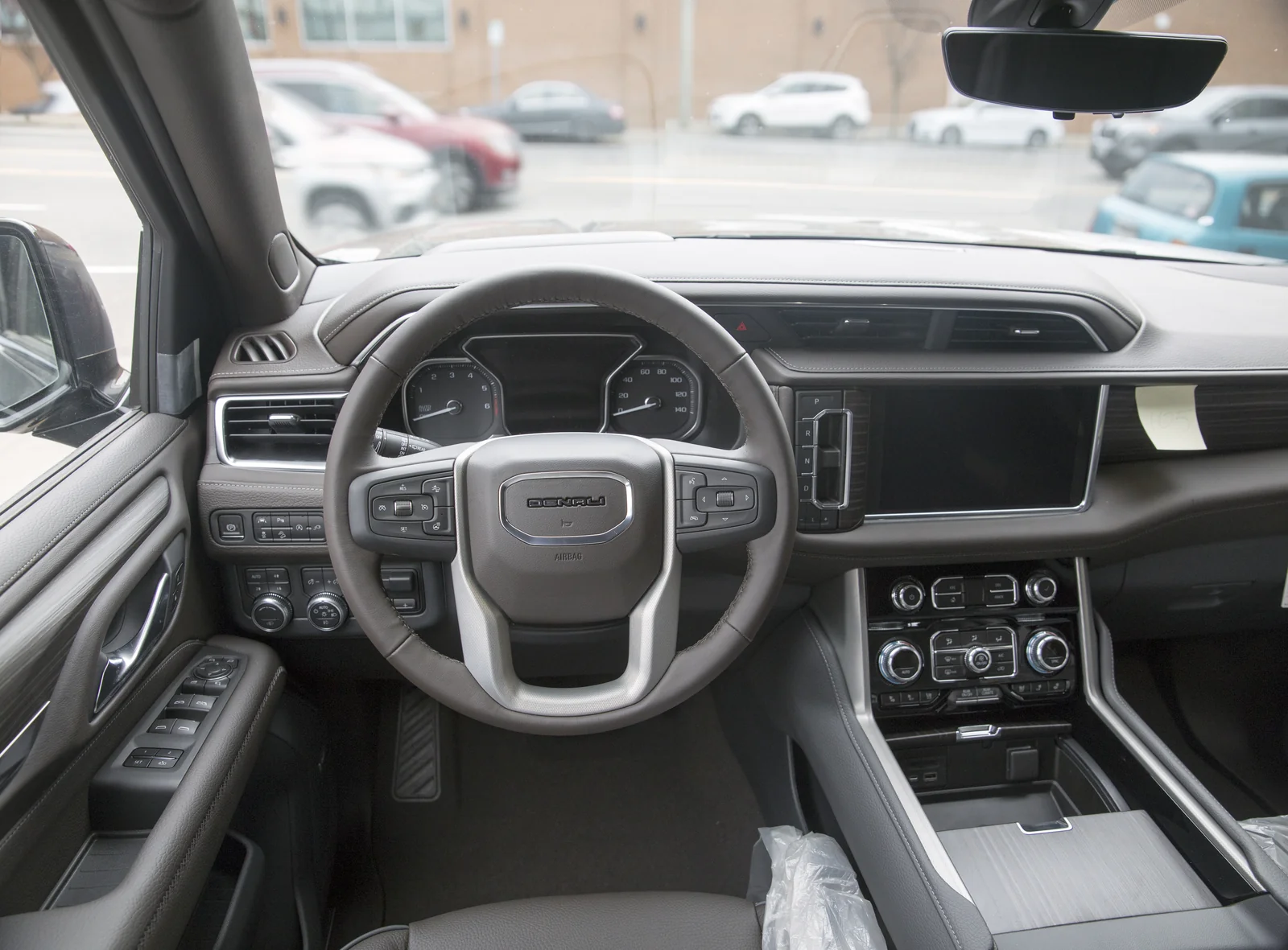 The dashboard and front cabin of a 2021 GMC Yukon Denali, showing the centre console and outlets referenced for living-in-it cargo and power features.