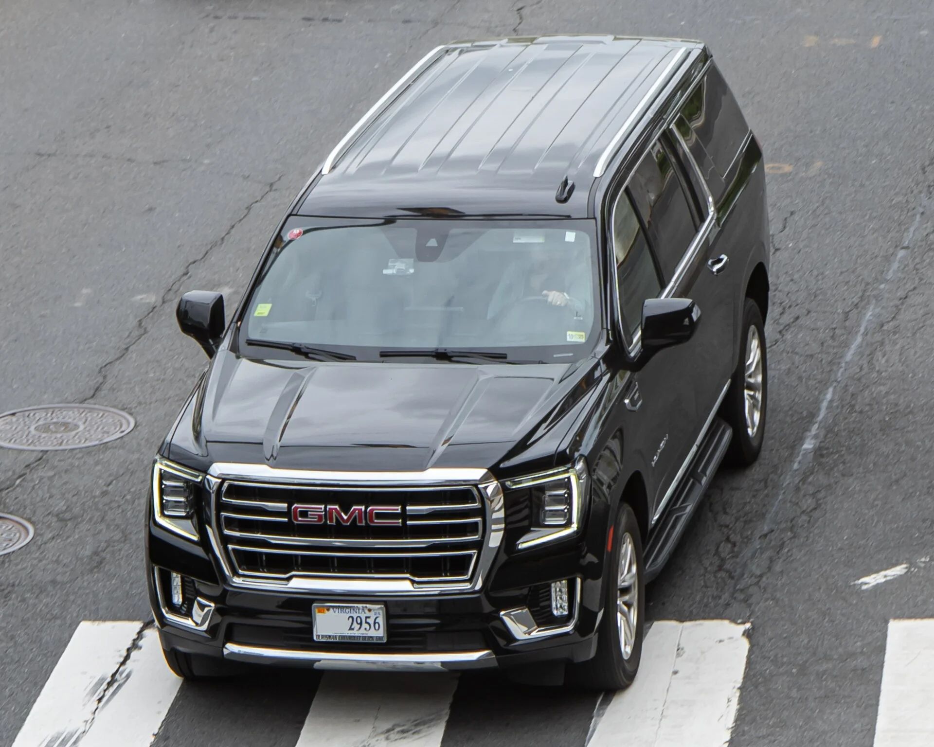 A black GMC Yukon XL full-size SUV parked at a kerb in a front three-quarter view, the long-wheelbase Yukon used for towing a travel trailer.