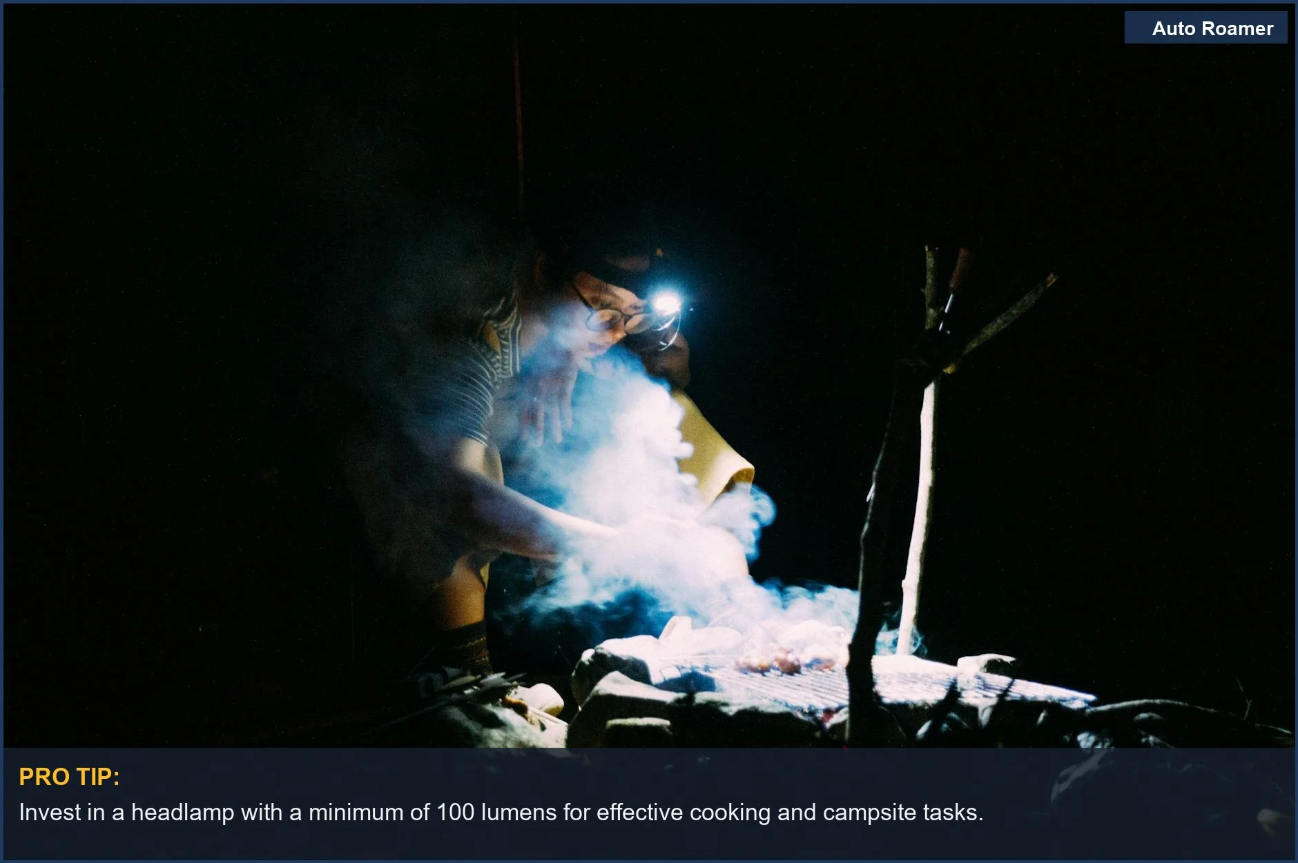Headlamp buying guide: Person cooking at a smoky campfire at night, illuminated by a headlamp.