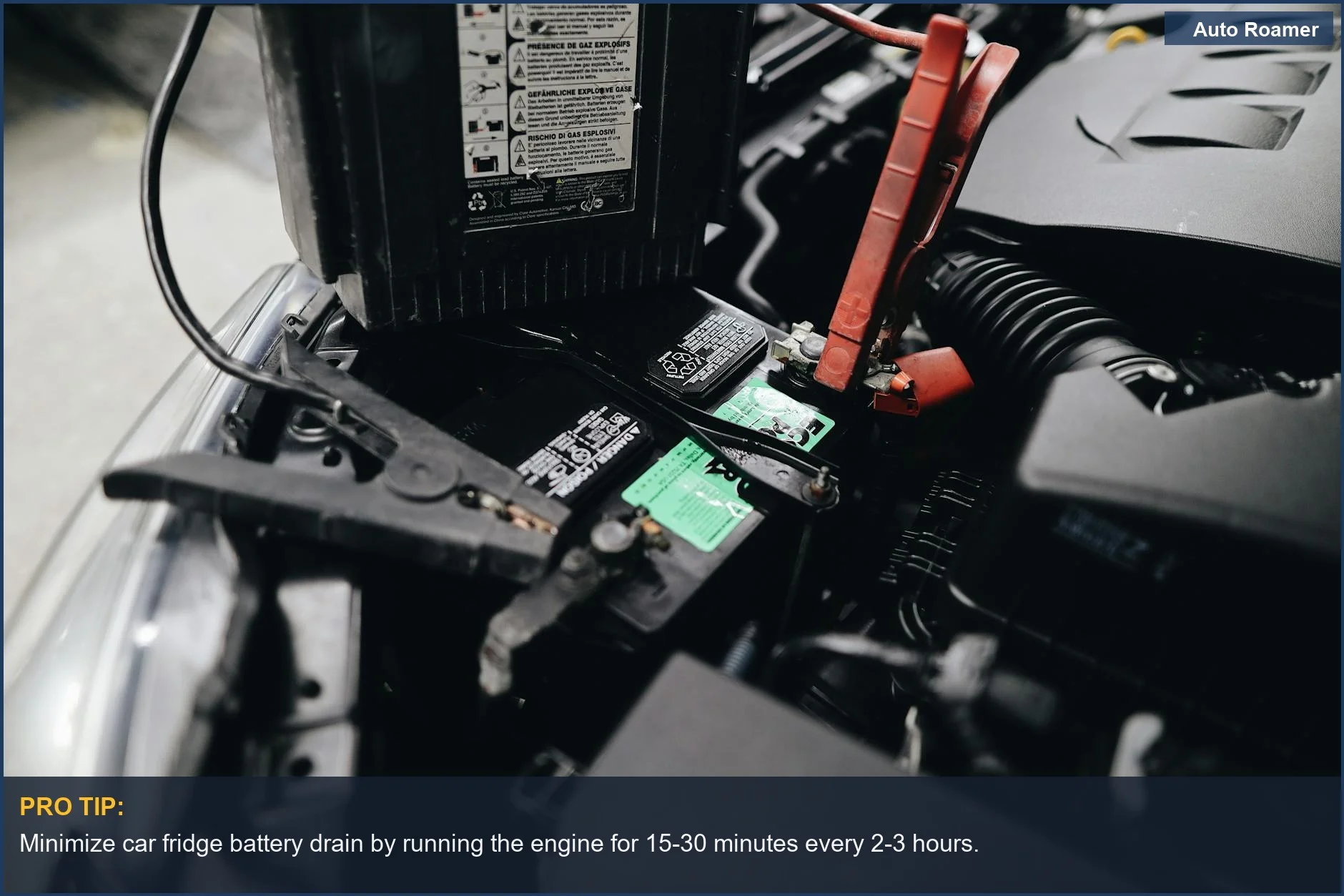 Close-up of car battery being jump-started with cables in engine bay, highlighting road trip cooler power needs.