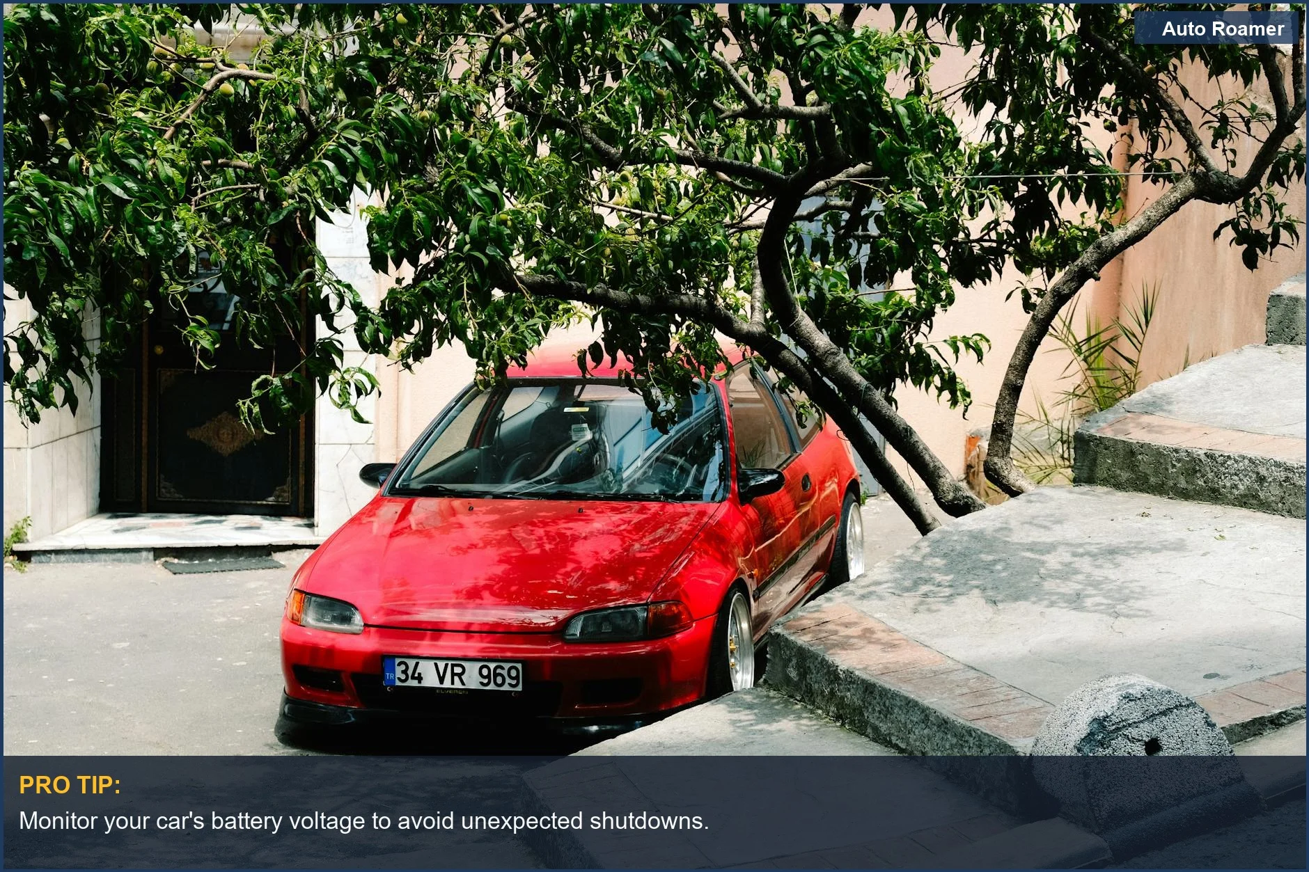 Red hatchback parked under a tree in the city, suggesting effective AC management.