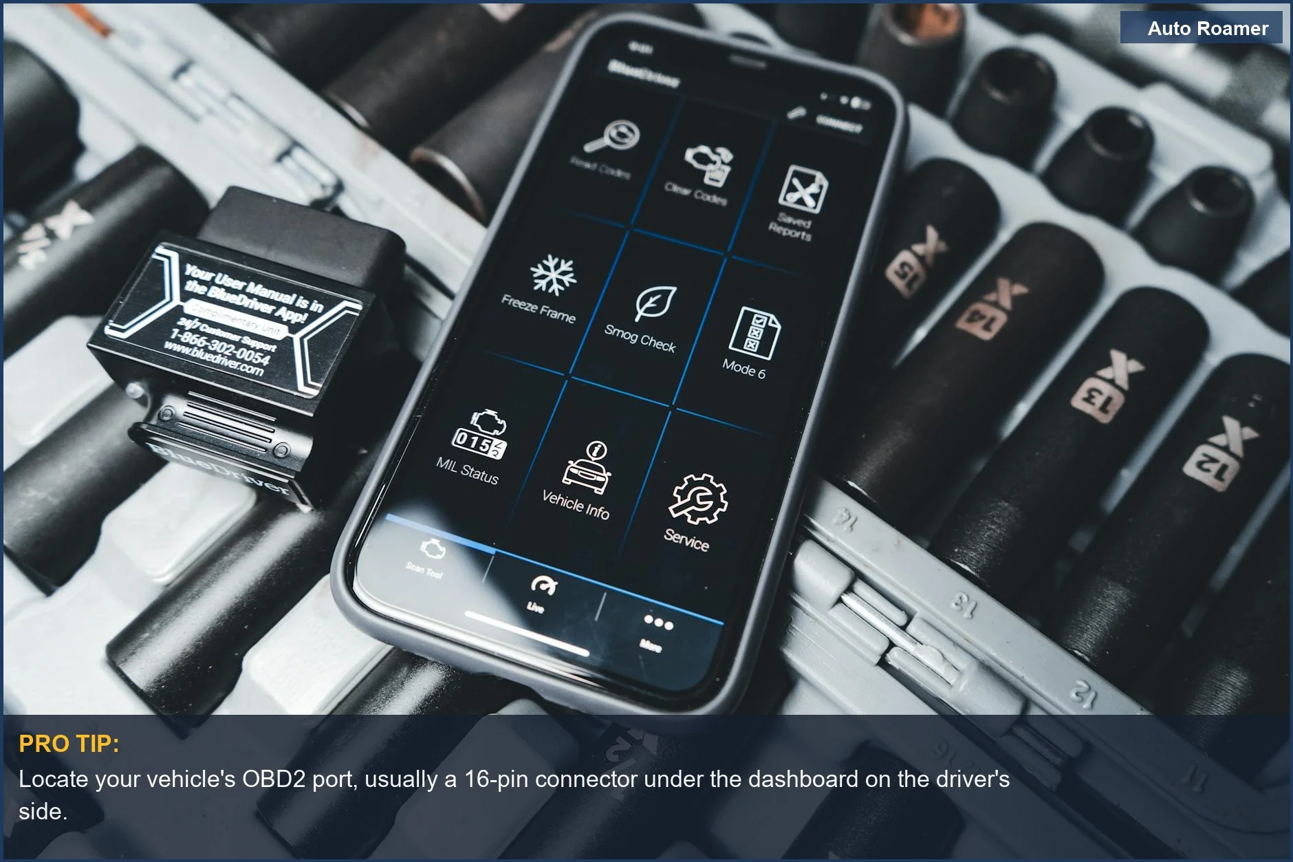 Smartphone displays a car diagnostic app connected to an OBD2 scanner in a garage.