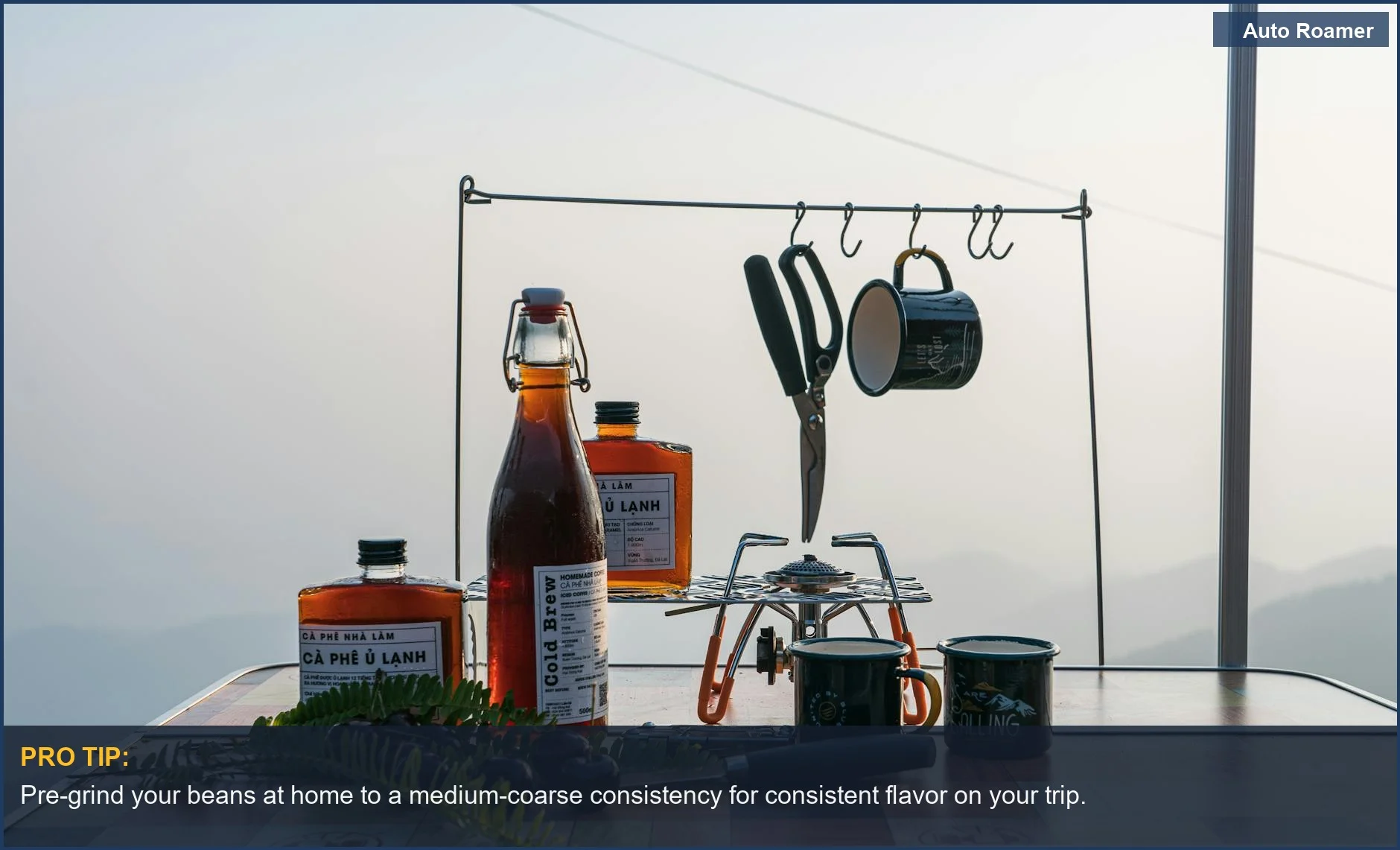 Essential camping coffee setup with brewing gear on a table, mountains in background.