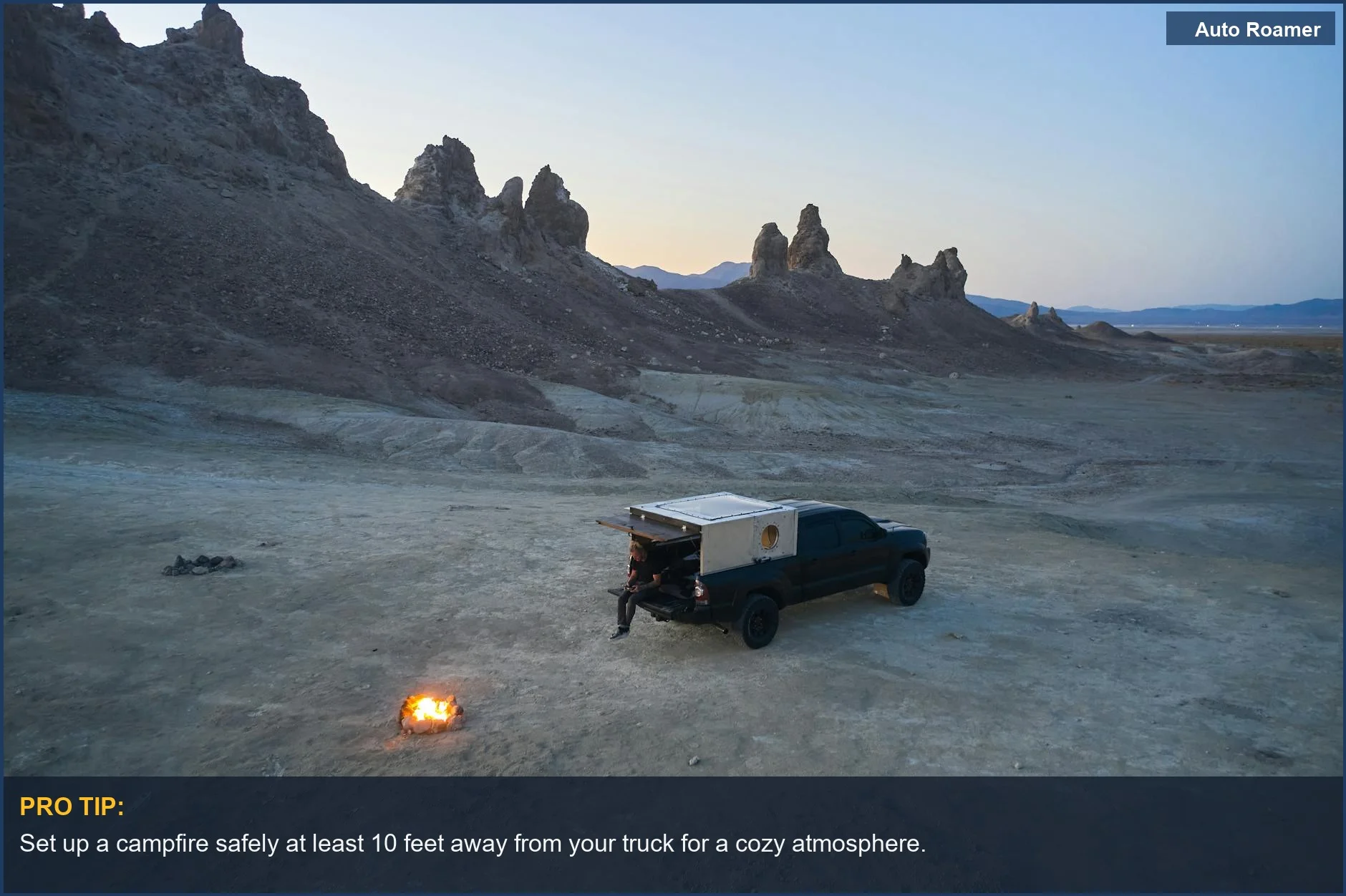 Tranquil desert camping scene with a pickup truck and campfire at dusk in Trona Pinnacles.
