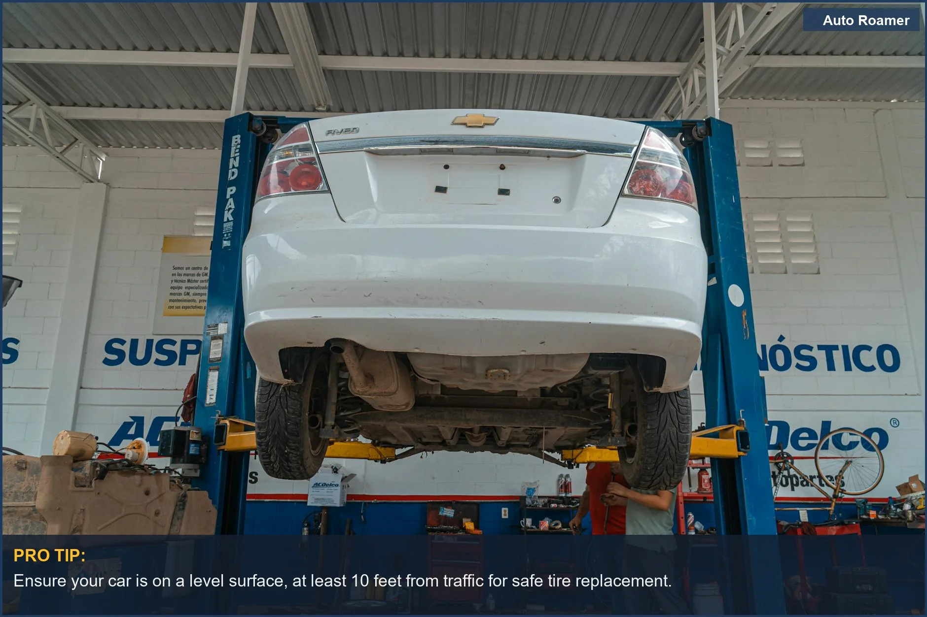 White Chevrolet car elevated on a lift in an automotive repair shop, ready for tire service.