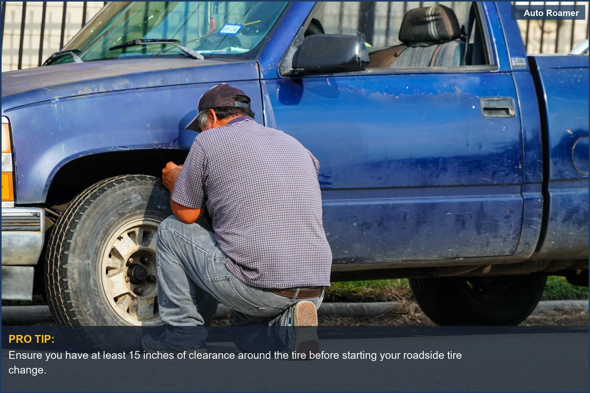 Man performing a roadside tire change on a blue truck in sunny Houston, Texas.