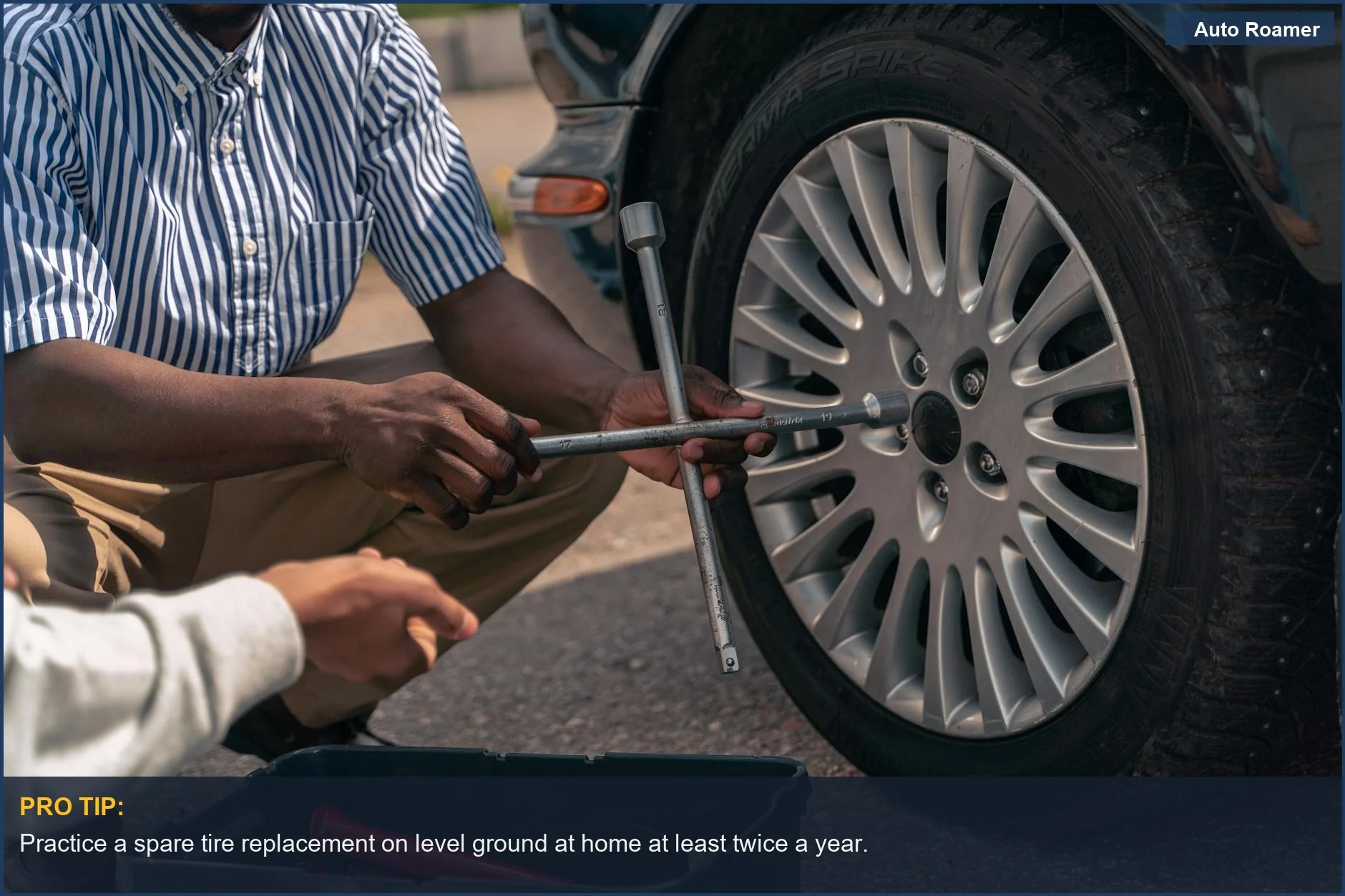 Adult teaching a teenager the process of a spare tire replacement on a vehicle.